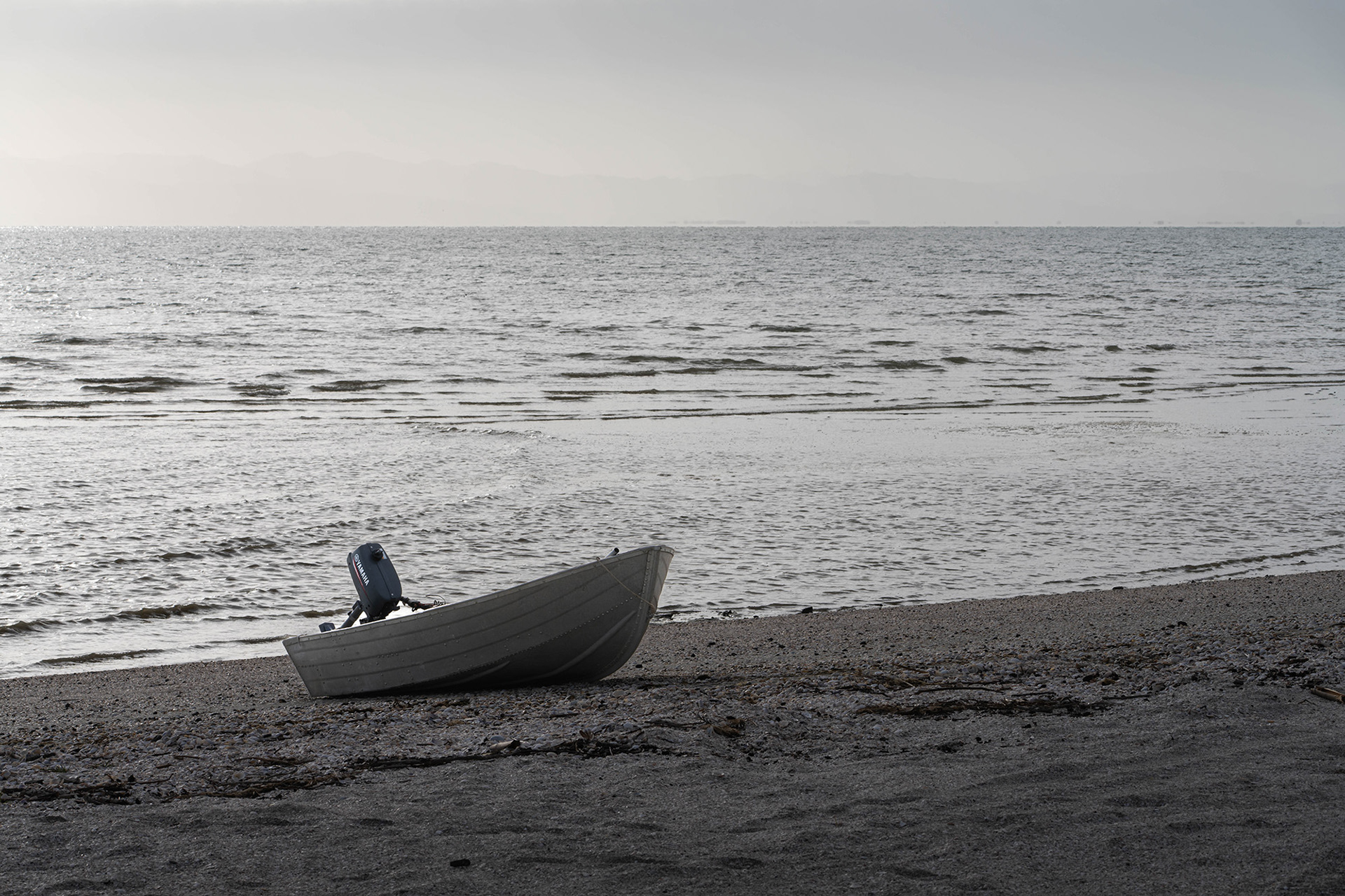 A solitary boat on the beach caught as a silhouette with the sun behind