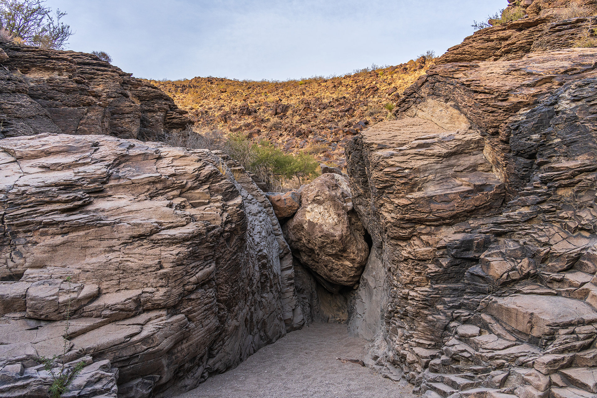 Landscape image of a large boulder wedged in the middle of the rock canyon