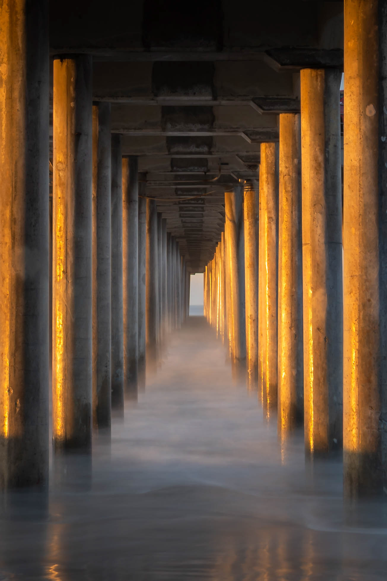 Symmetrical piles beneath the Huntington Beach pier reflecting the early morning sunshine