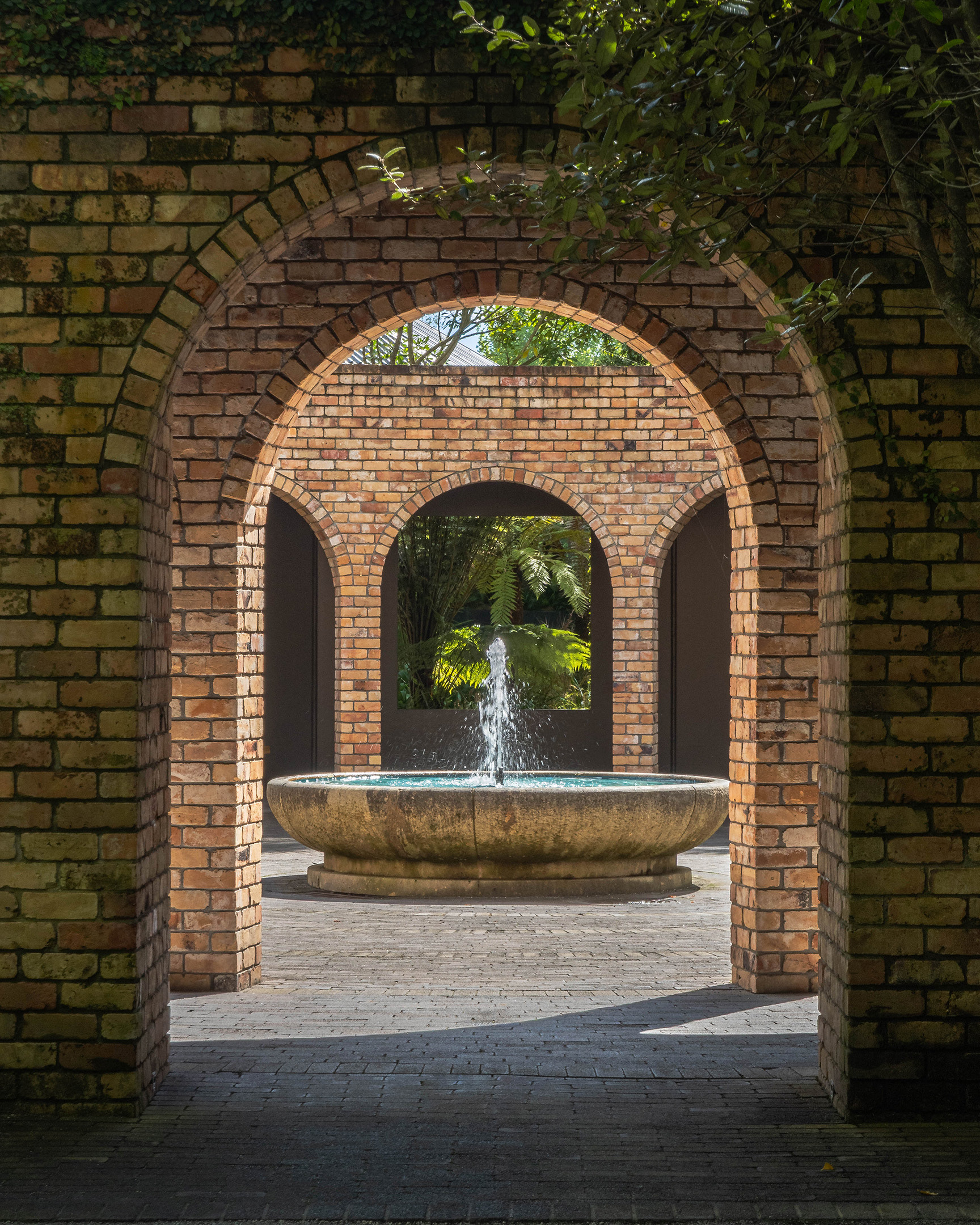 View of a fountain at Hamilton Gardens framed by brick arches
