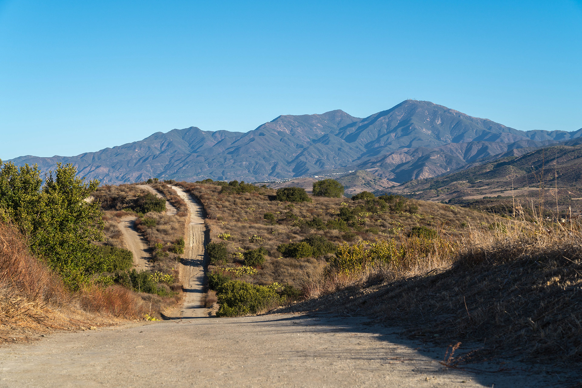 California landscape of a ridge trail leading to the distant Saddleback mountains