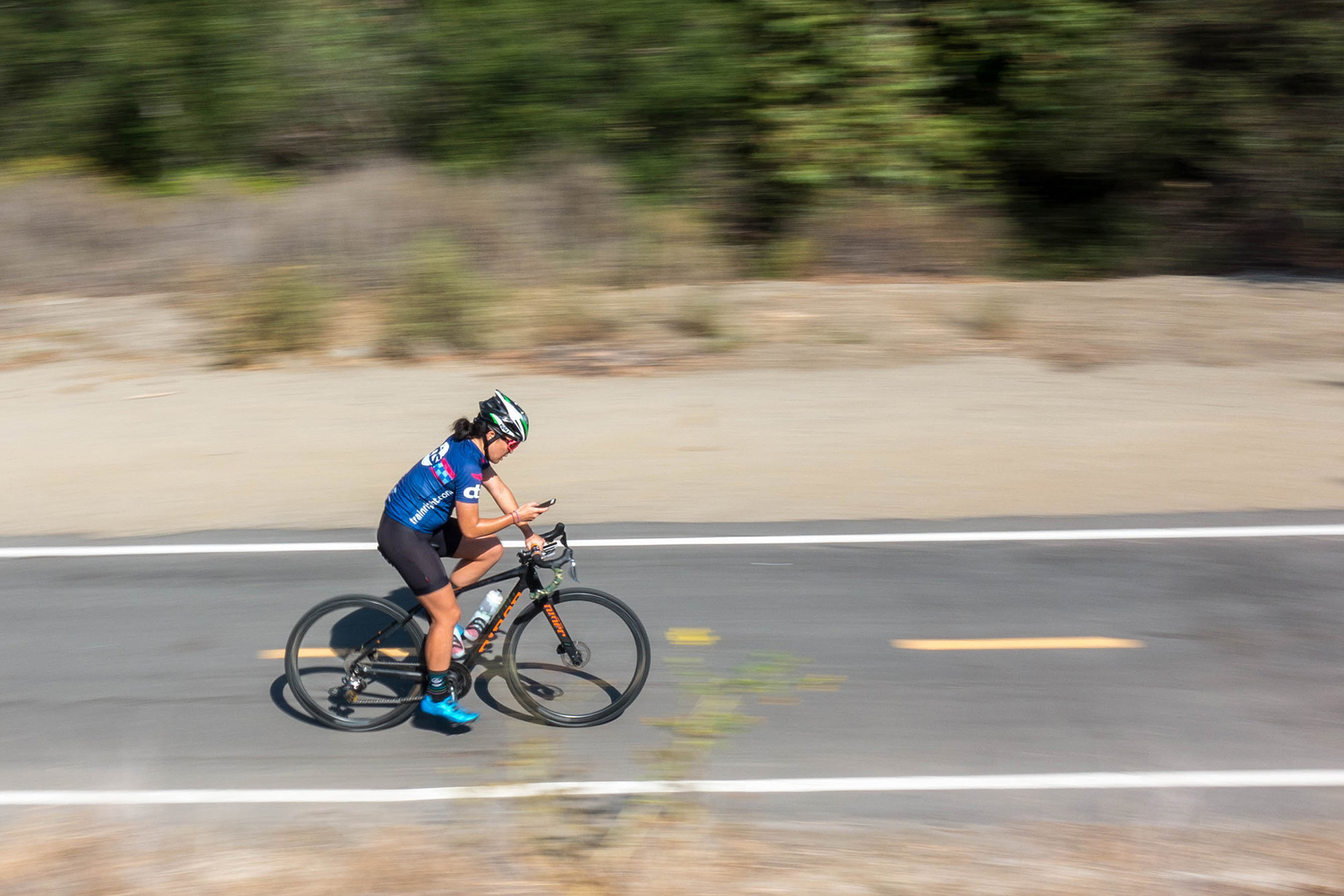 Cyclist on a trail in Southern California districted by a cell phone