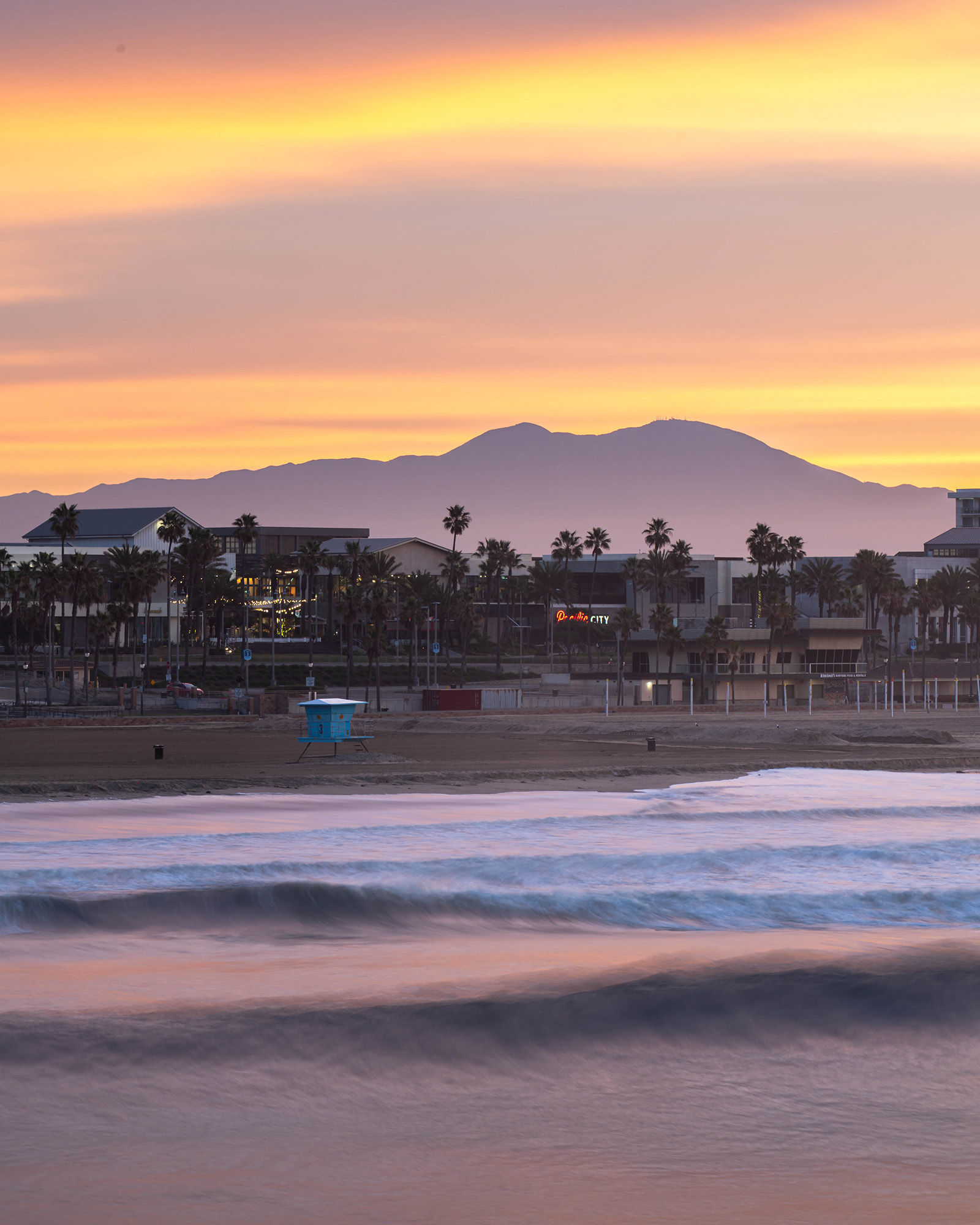 A view of Huntington Beach taken at sunrise from the pier with the Saddleback mountains in the background