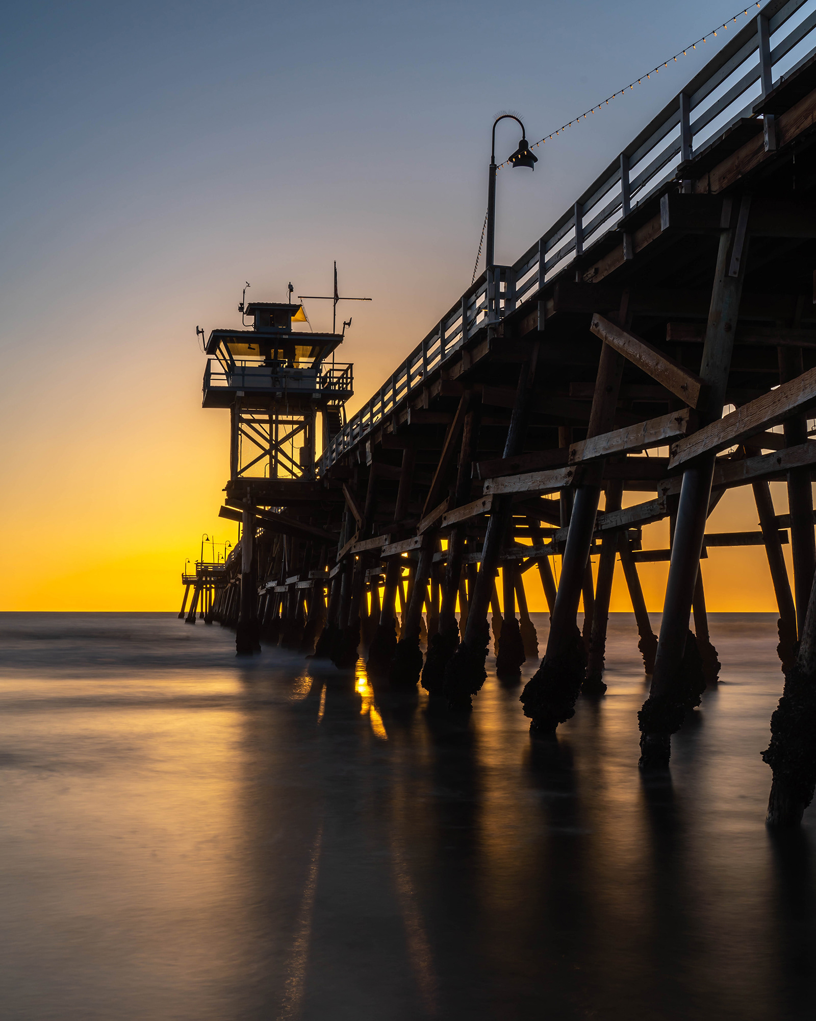 California seascape long exposure image showing a pier at sunset