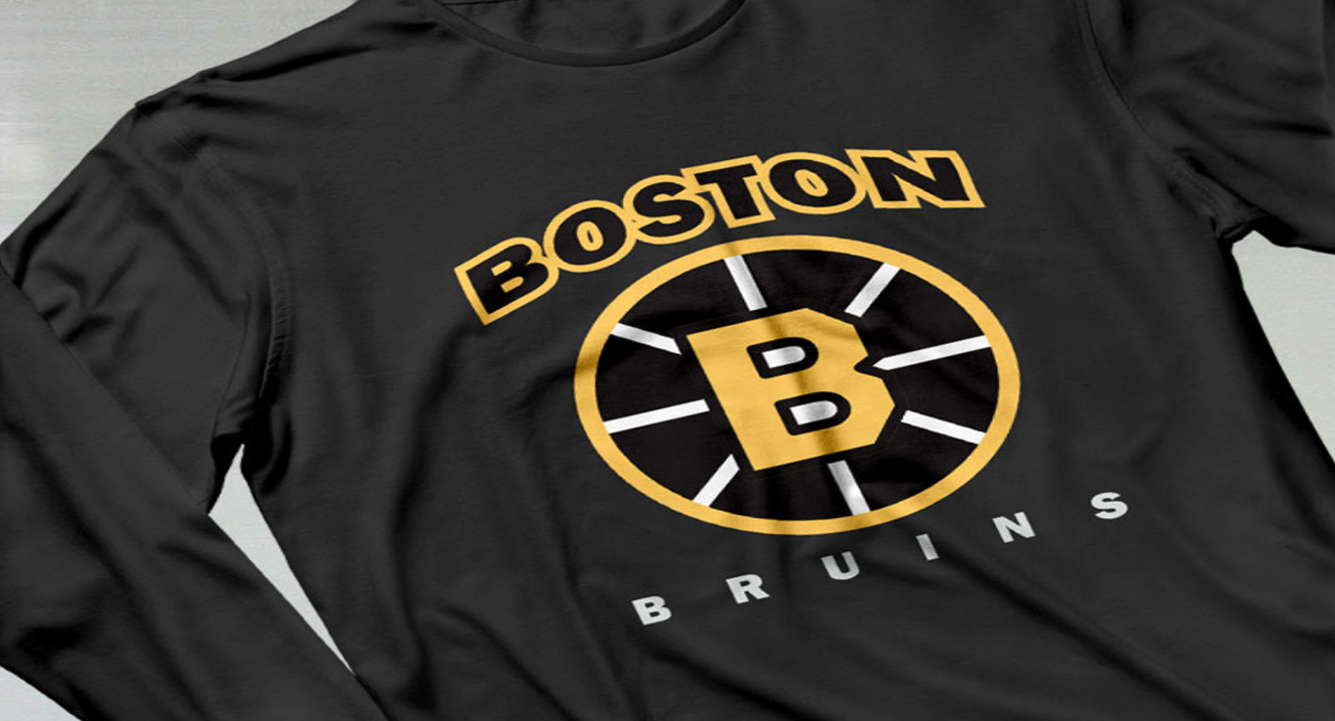 Black long-sleeve tee featuring the Boston Bruins logo, screen printed in high contrast white and gold for sports apparel.