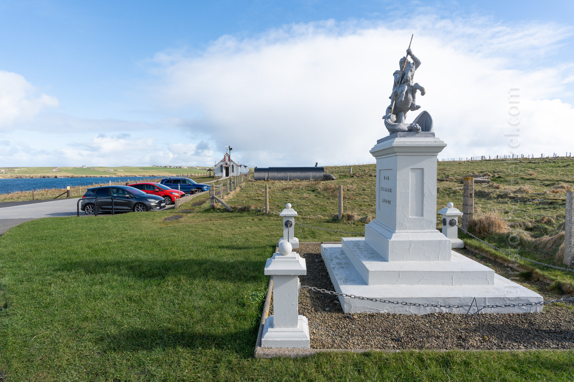 Chapel in the background on the left; war memorial featuring a sculpture of St. George slaying the dragon on the right.