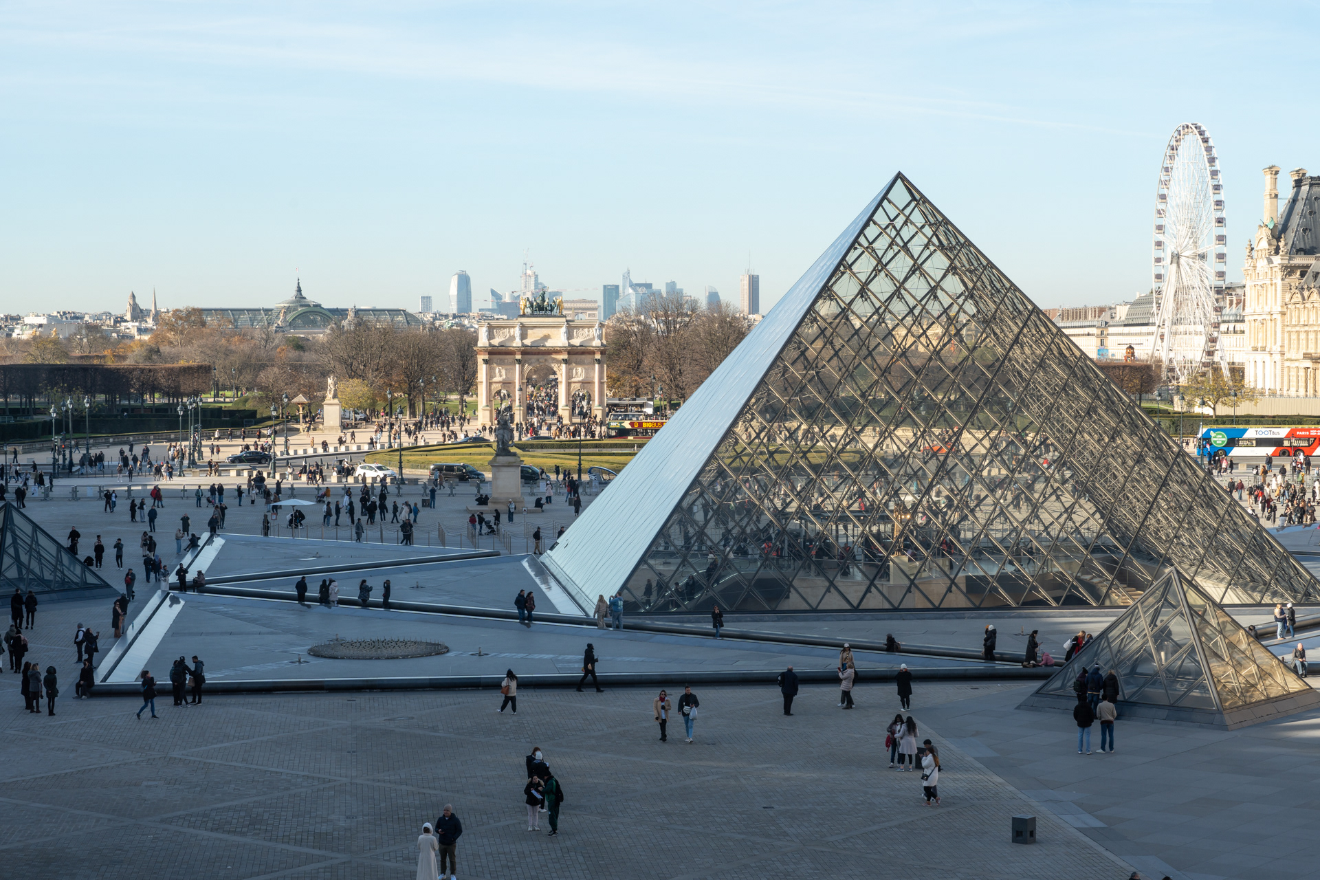 The Louvre pyramid, designed by renowned architect I. M. Pei in the 1980s as a new main entrance to the museum. The Arc de Triomphe du Carrousel is in the background and the gardens of the Jardin des Tuileries beyond that. The roof of the Grand Palais is in the far distance.