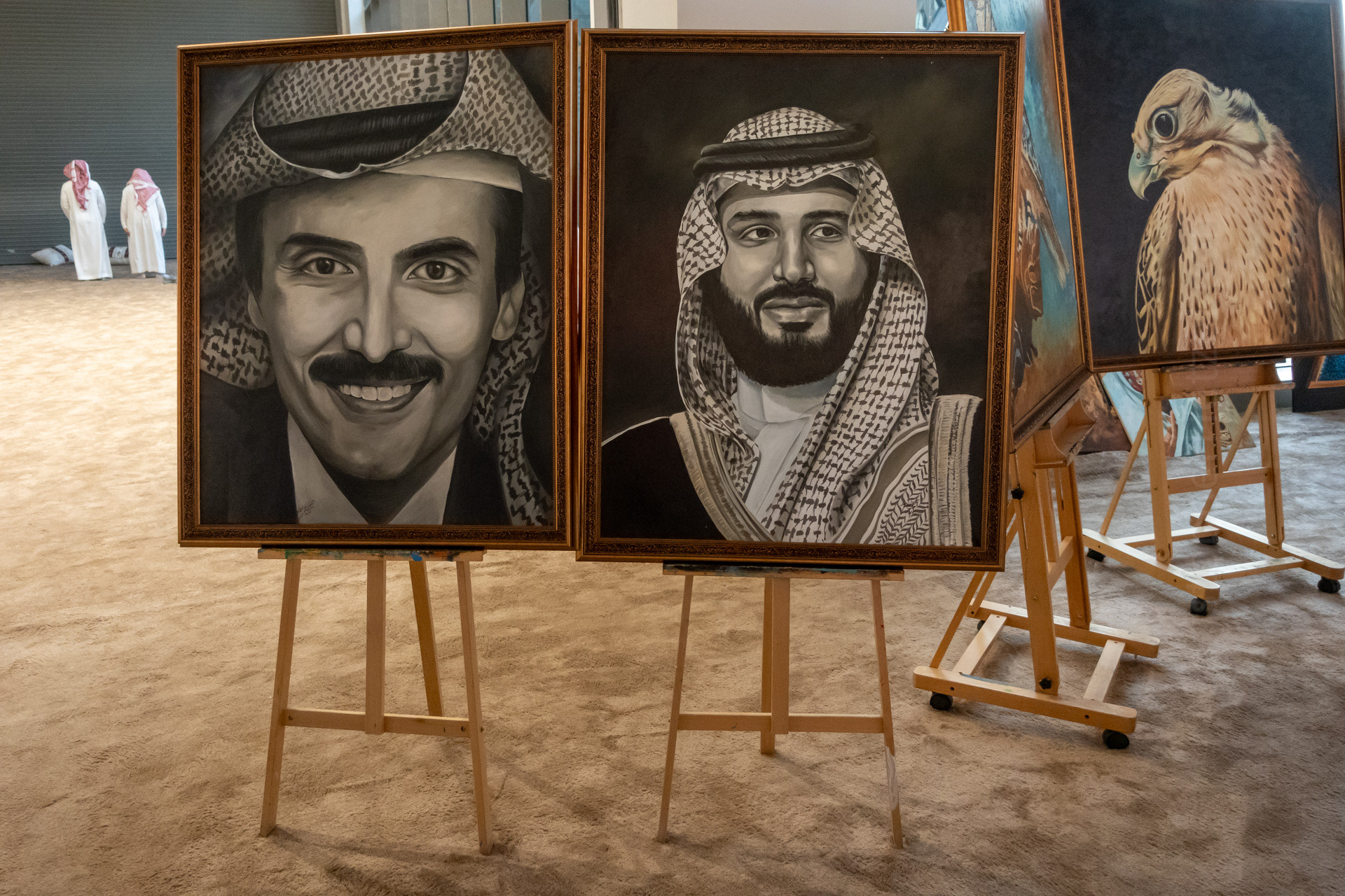 The painting on the right is of Mohammed bin Salman Al Saud (known commonly as "MBS"). He's the Crown Prince and Prime Minister of Saudi Arabia and the de facto ruler of the Kingdom. He is the heir apparent to the Saudi throne and the seventh son of King Salman of Saudi Arabia and grandson of the nation's founder, King Abdulaziz.