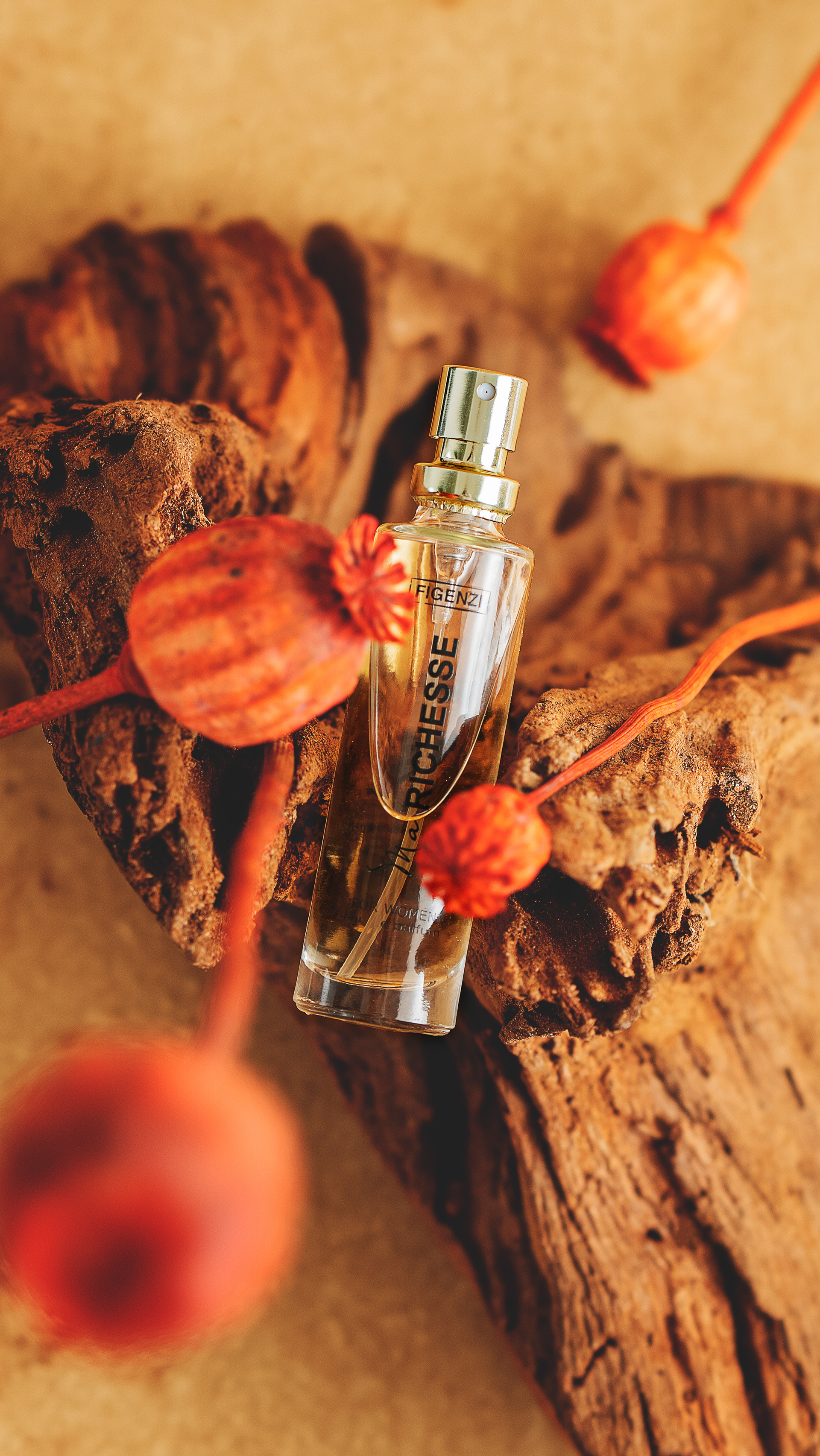 photo de produit flacon eau de parfum pour femme posé sur un rocher de bois flotté avec fleurs de pavot séchée