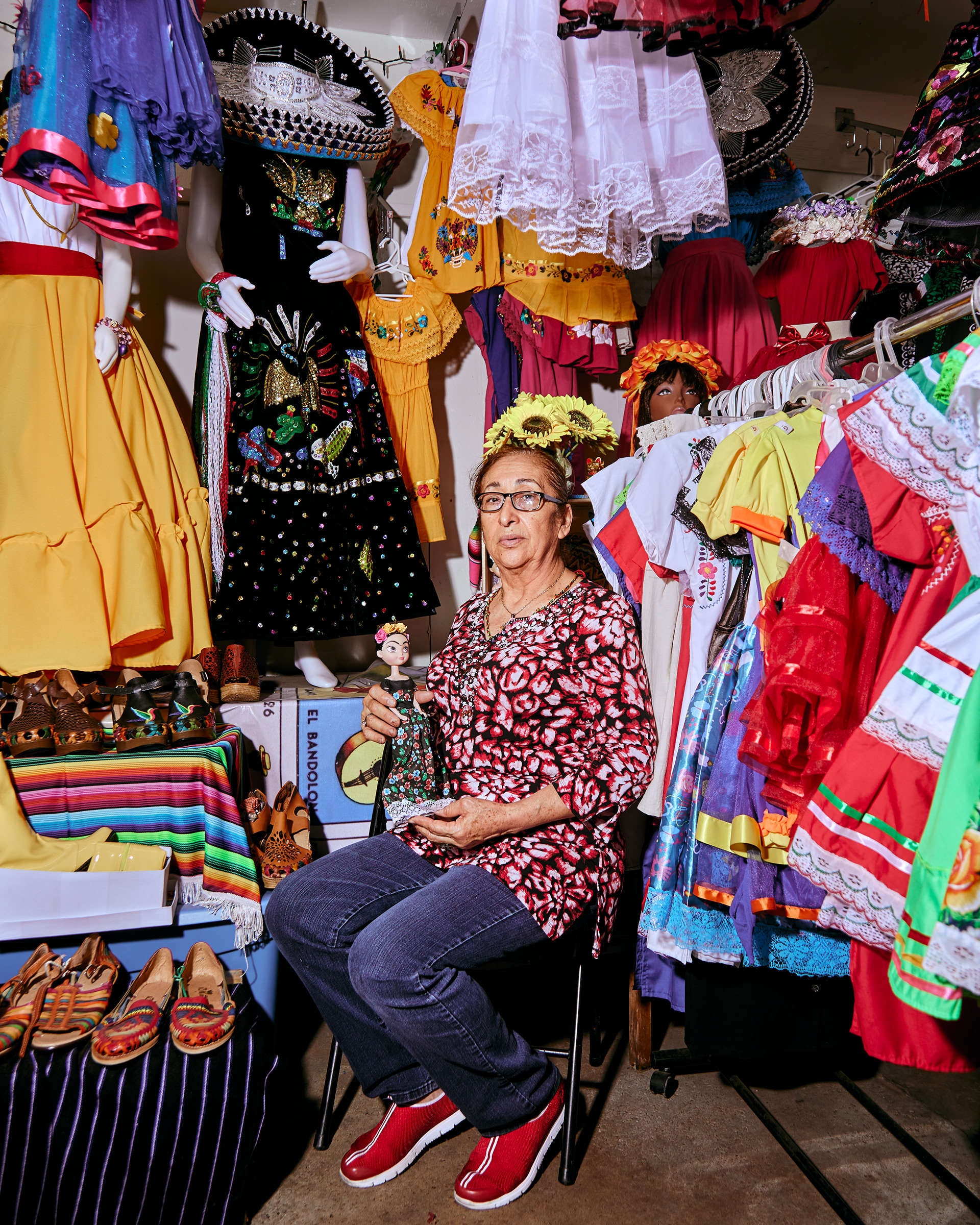 Doña Lupe posing with a doll in her both at Buey Y Vaca Flea Market