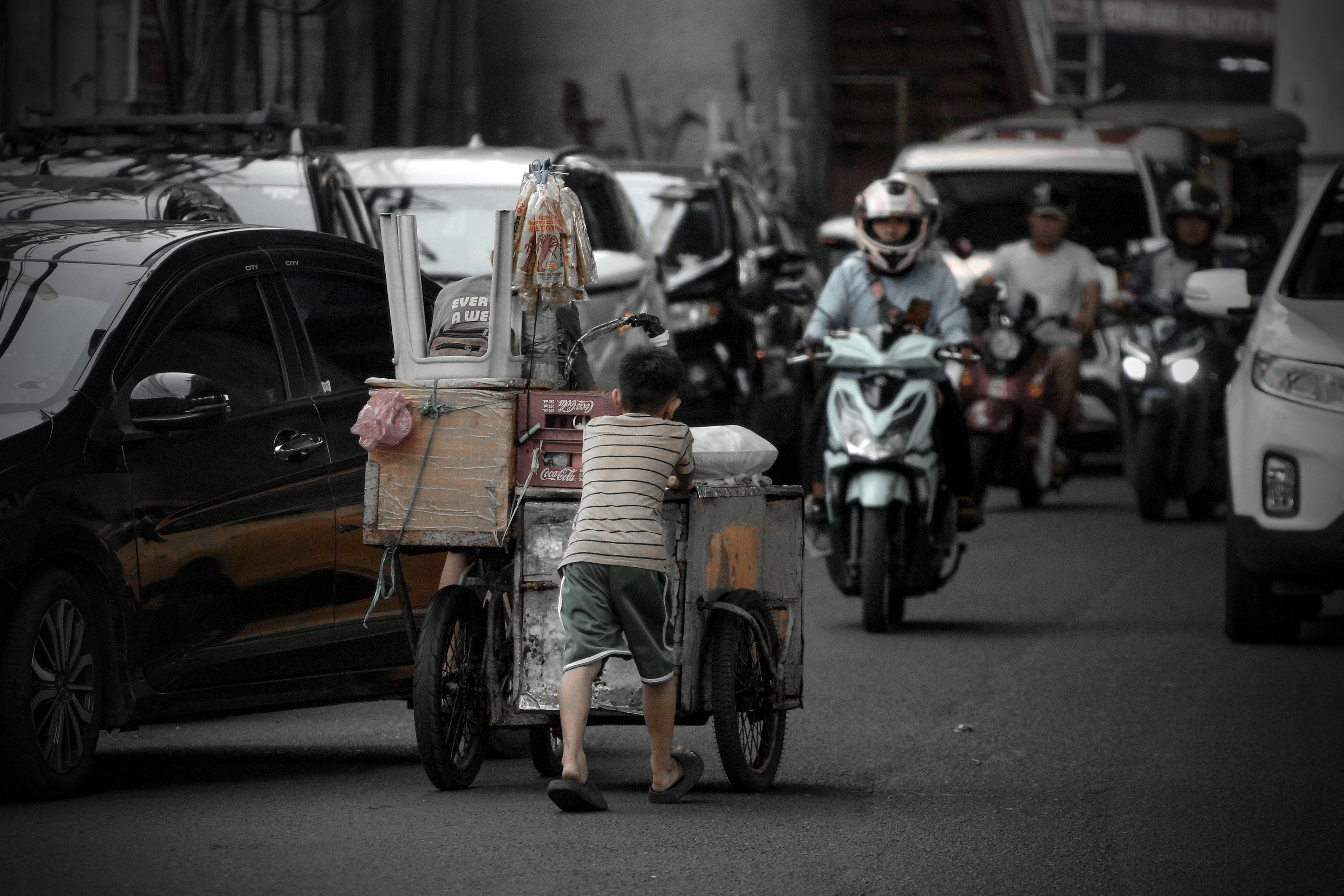車道を逆行して父親が乗る行商の3輪自転車を押す子ども。数分前に飲み水を与えられていた。
