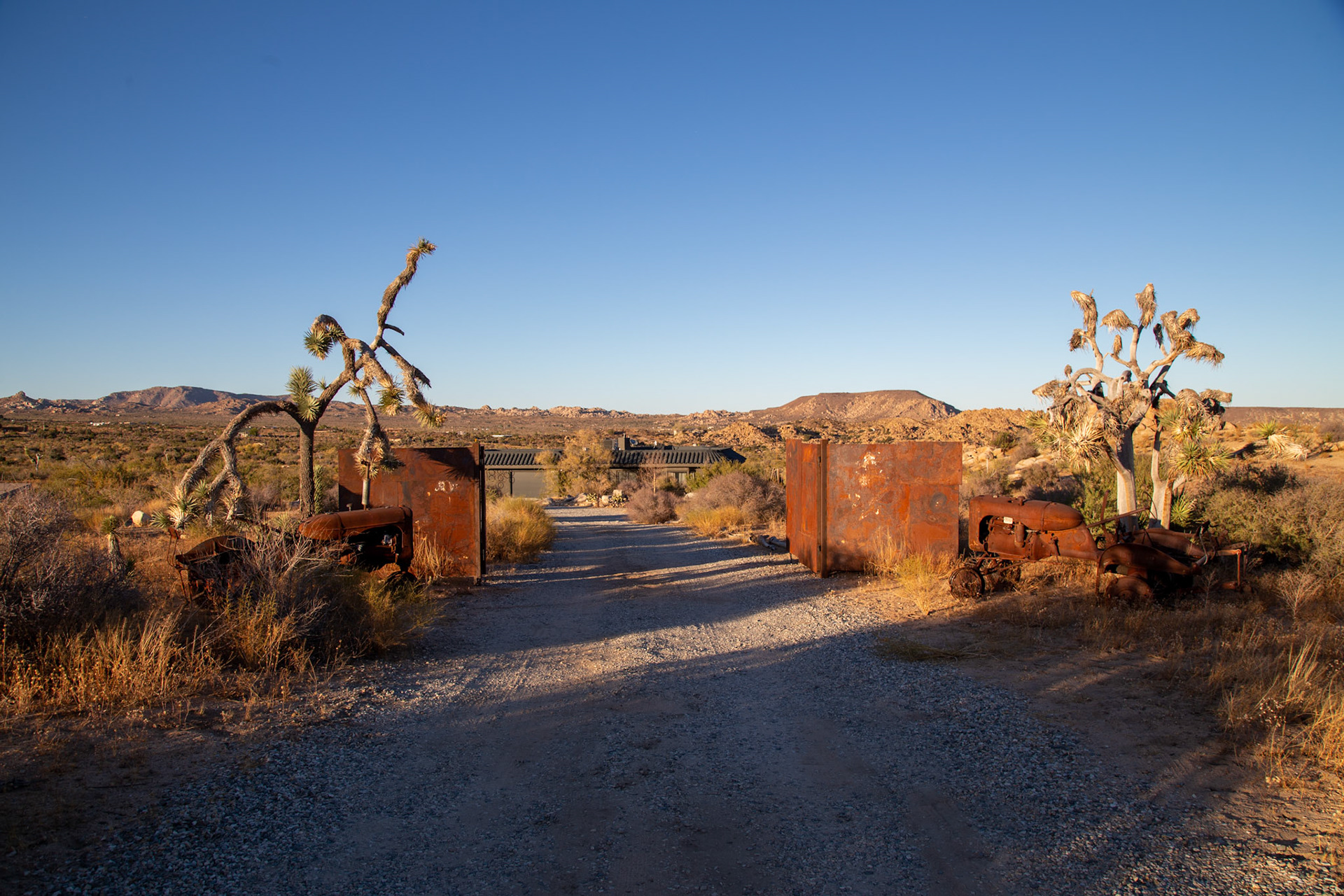 At the entry to our Airbnb in Pioneertown: flanked by two old tractors and large iron gate