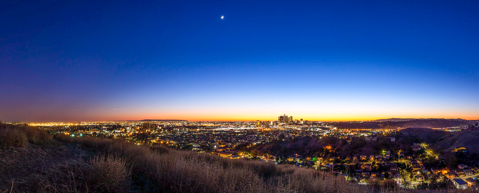 Just after sunset, the glow of the sun remians behind downtown LA, and the moon has already risen.