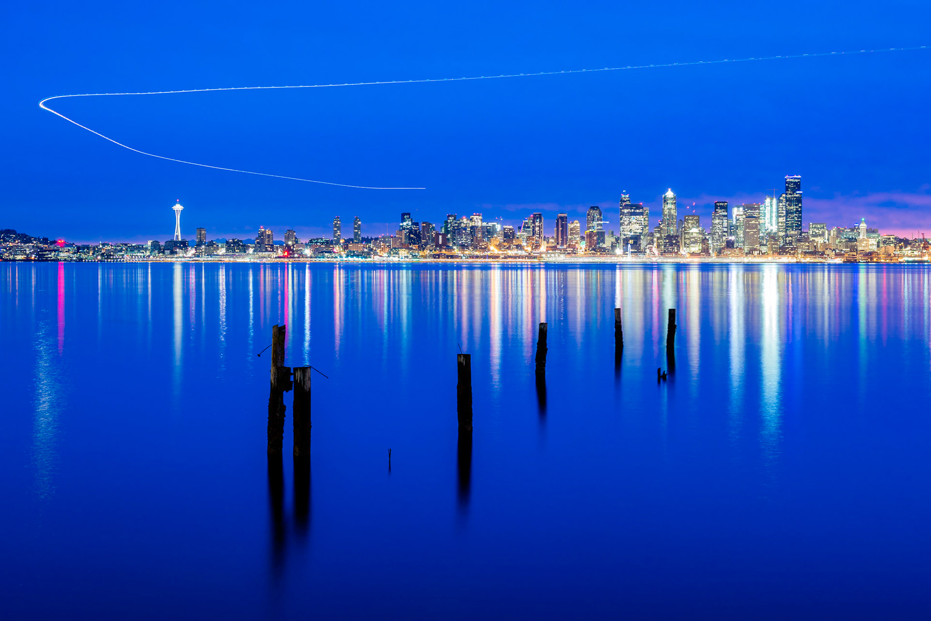 This is a composite of 7 images which capture the approach of an aircraft over Downtown Seattle to SEATAC Airport.