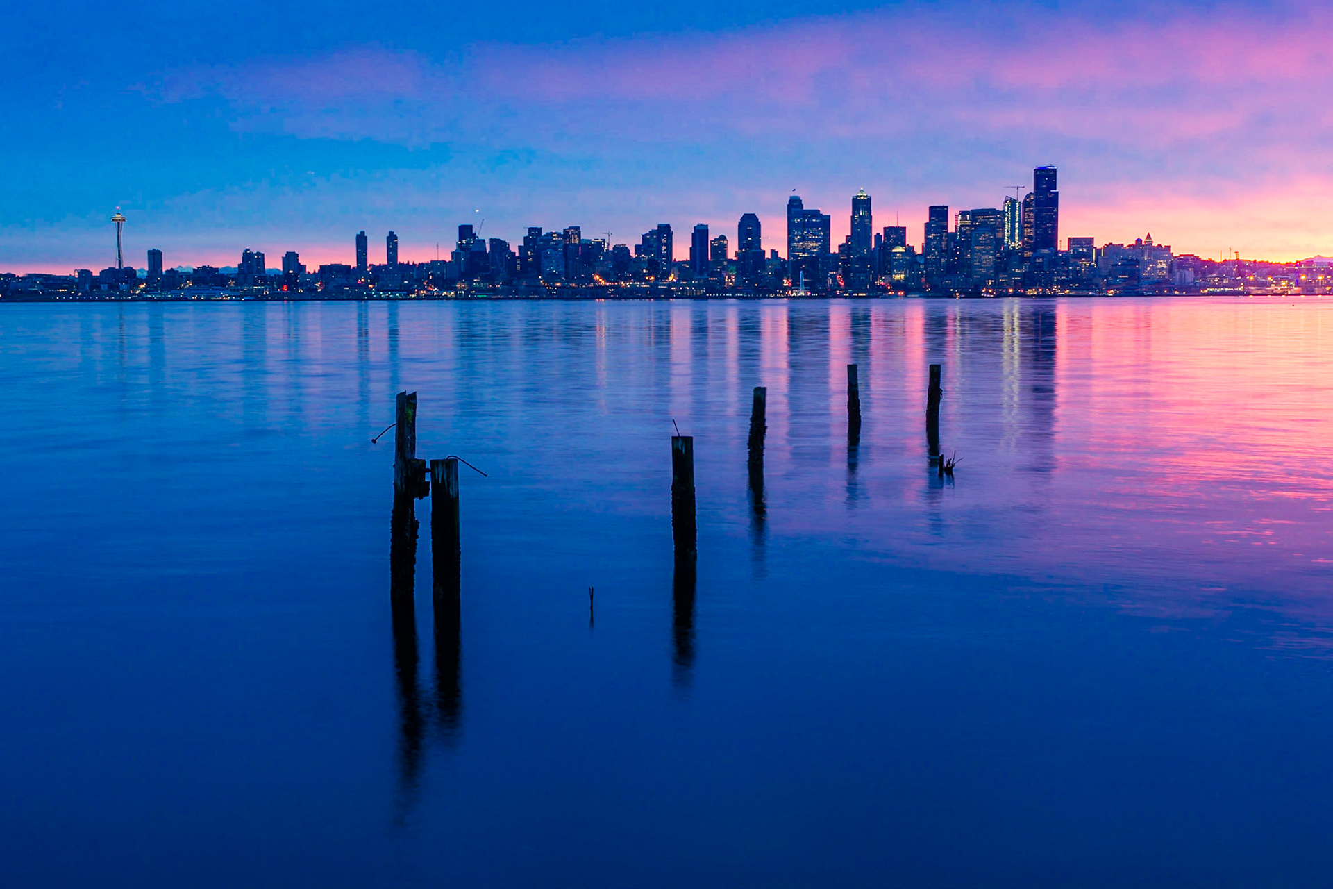 As the sun rises behind the city it begins to illuminate the clouds in a beautiful golden glow.