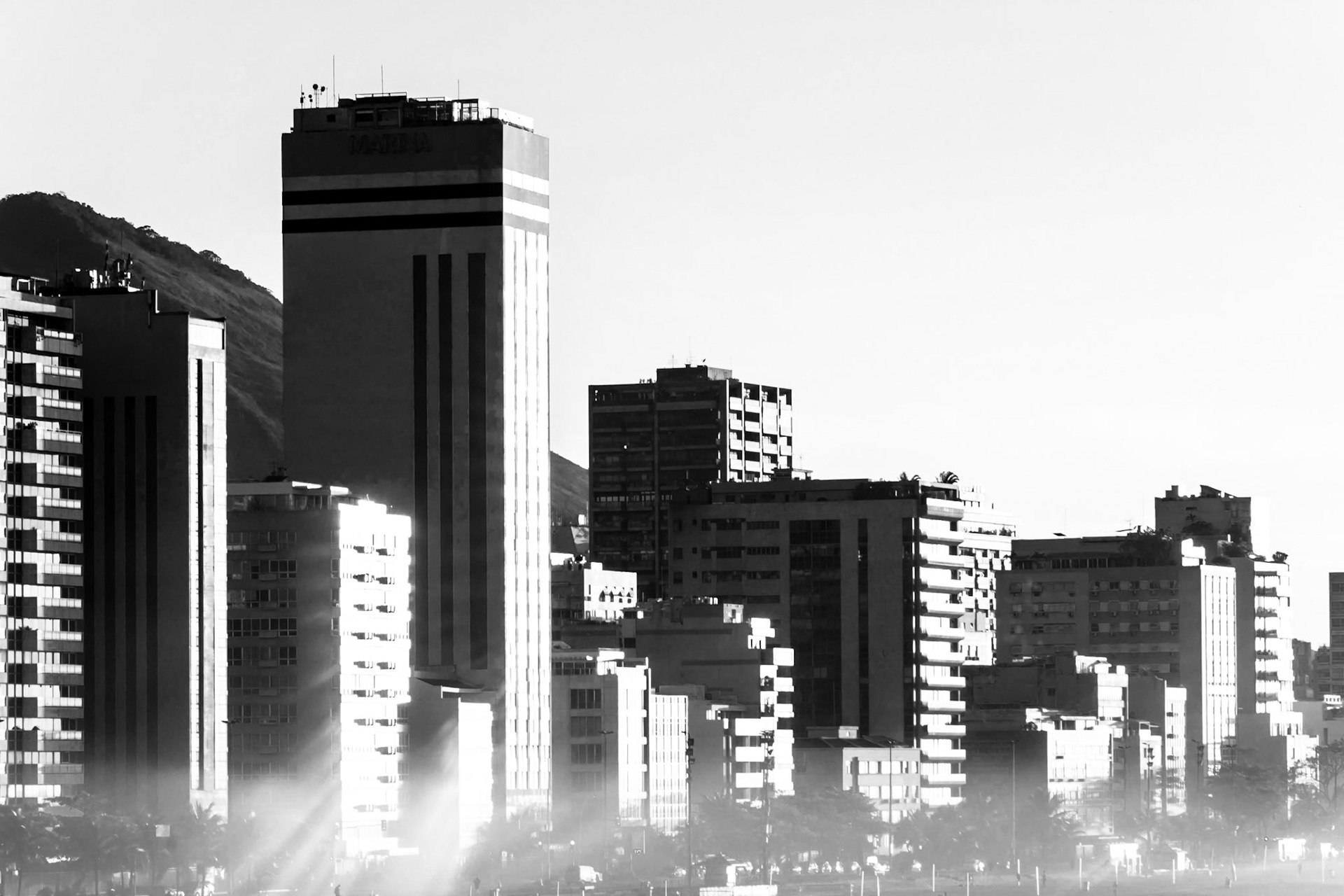 The sun has risen on the breaking waves at Ipanema Beach- the surf is strong enough to create a mist over the beach. This is a close-up of the apartments and hotels which overlook the beach.