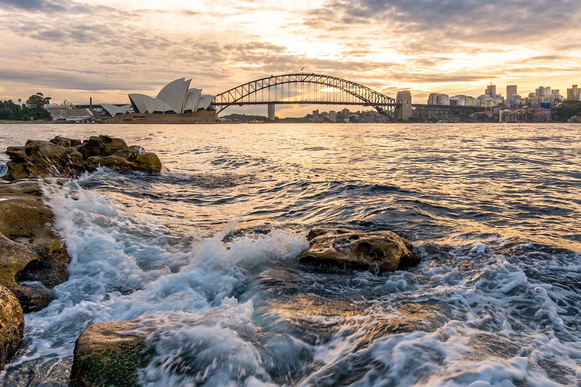 The sun sets behind the Harbour Bridge and Opera House in Sydney.