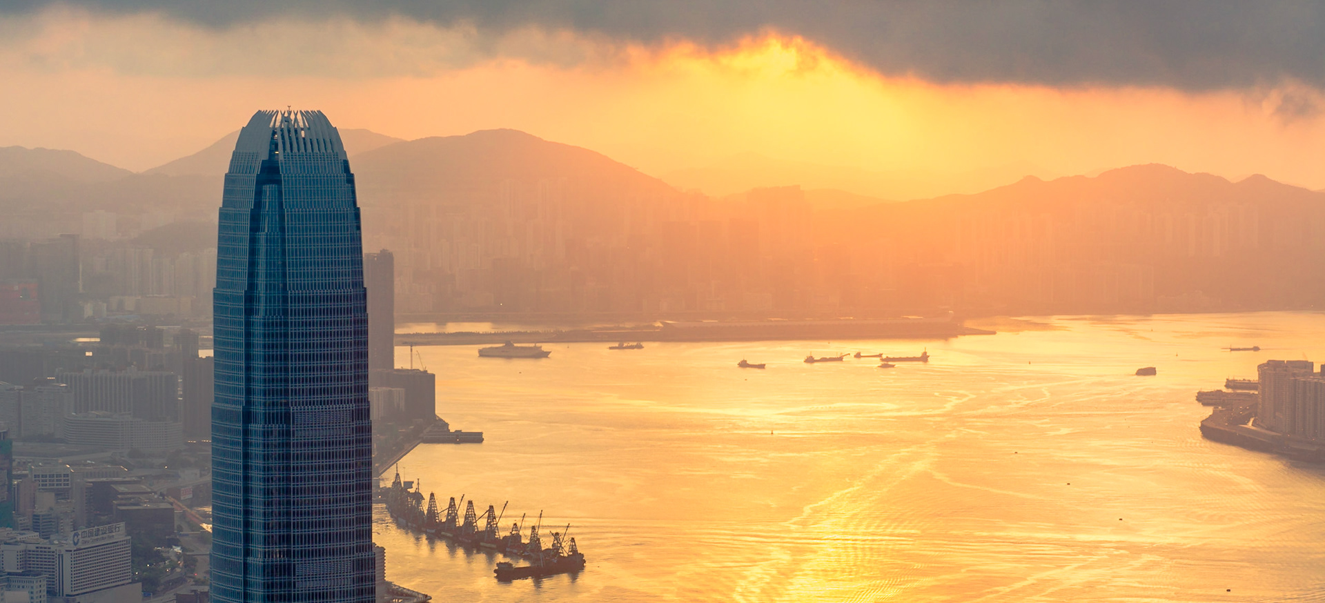 The Sun turns Kowloon Bay golden as it rises. Taken from the Victoria Peak viewpoint, tower two of the International Finance Centre looms over the bay.