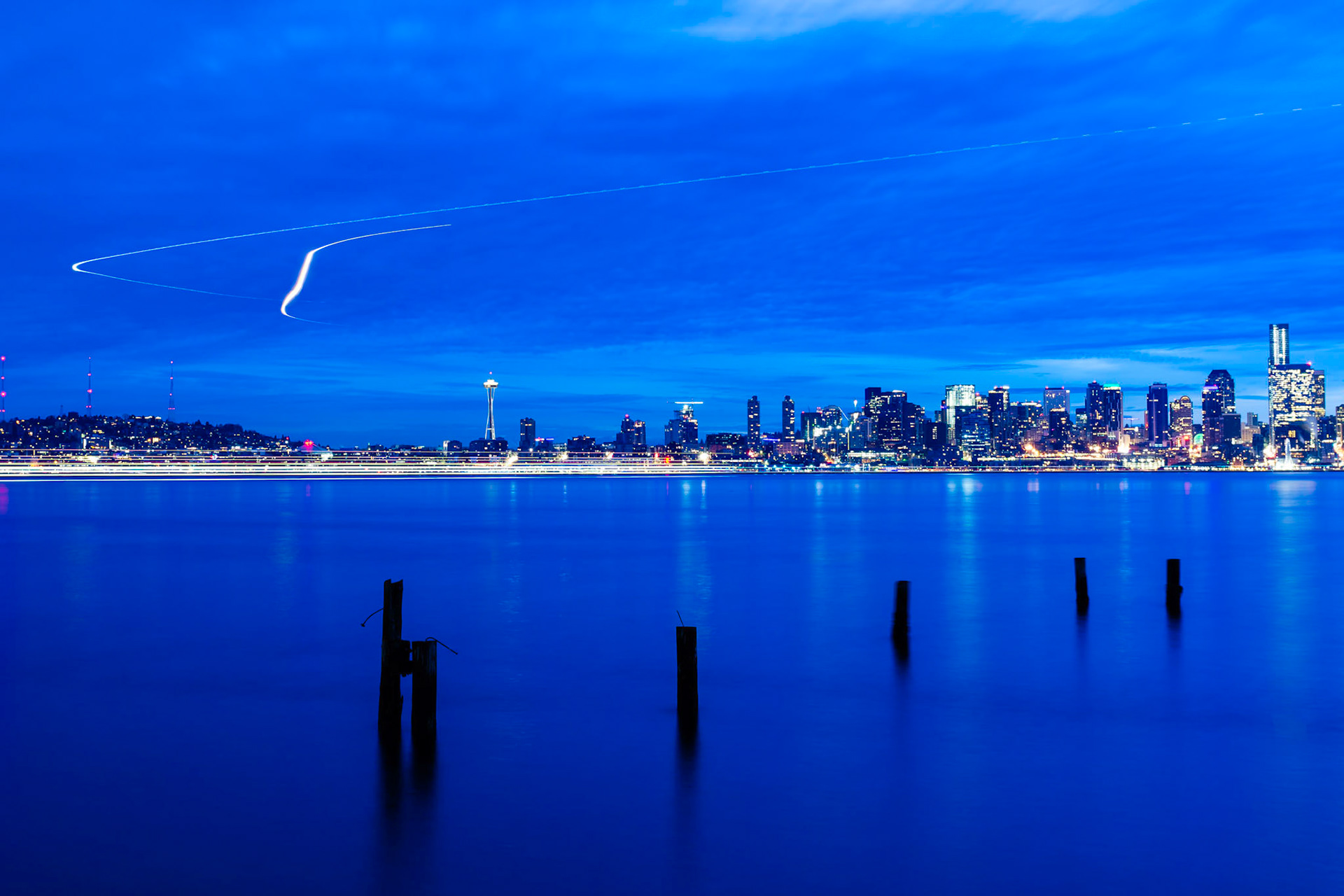 Sunrise in Seattle, Washington State, viewed from Seacrest Park across the bay to Downtown. Here, light trails from aircraft landing at Seattle-Tacoma International Airport are visible.