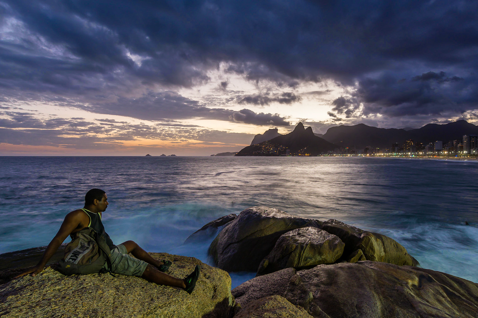 RIO DE JANEIRO, BRAZIL - APRIL 5 2015: Taken at Pedra do Arpoador, on the Eastern end of Ipanema beach, this man is lost in thought at the moment of sunset.
