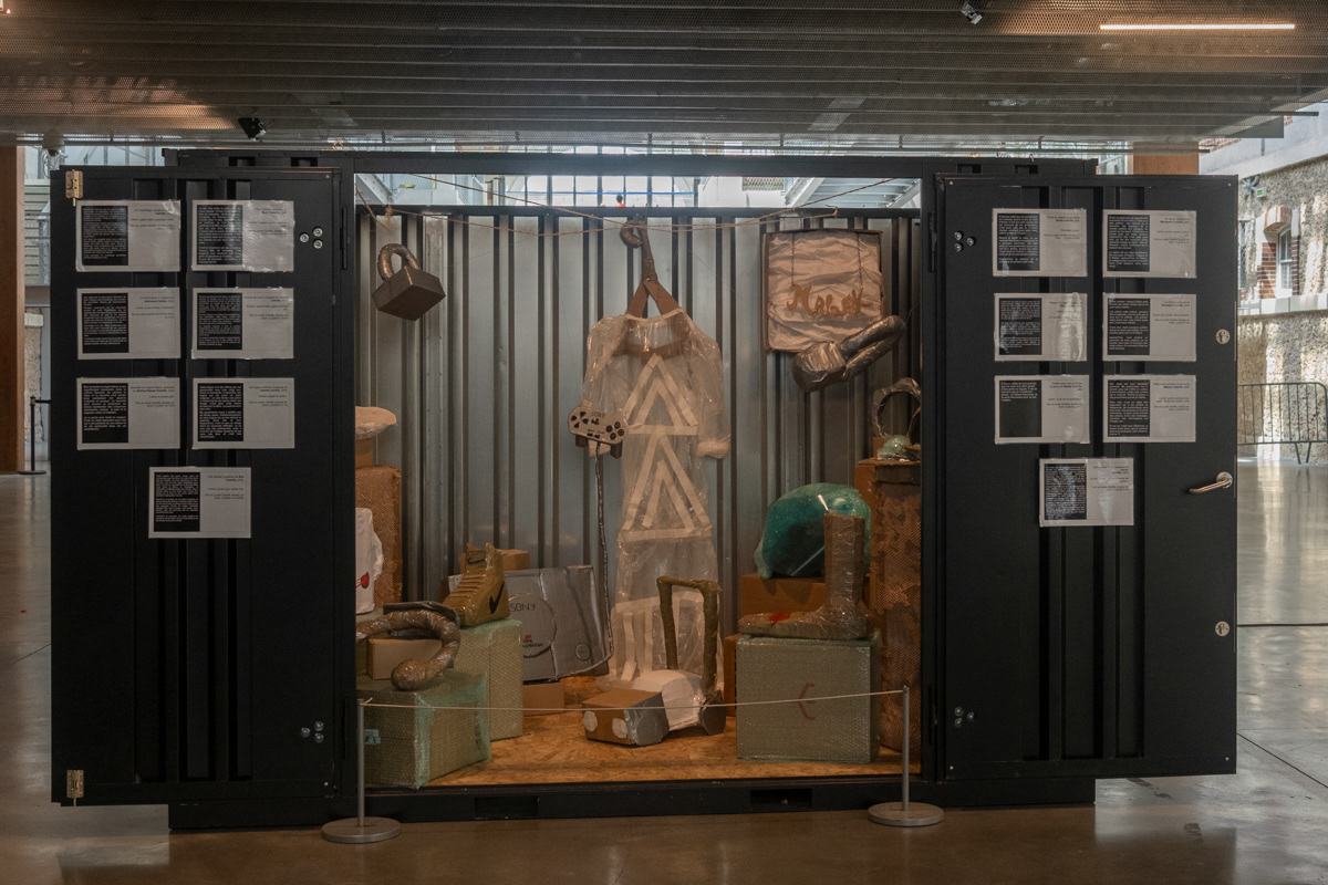 Vue de face du container. Chaque cartel a une partie descriptive classique et une partie émotionnelle racontant l'histoire de l'objet.