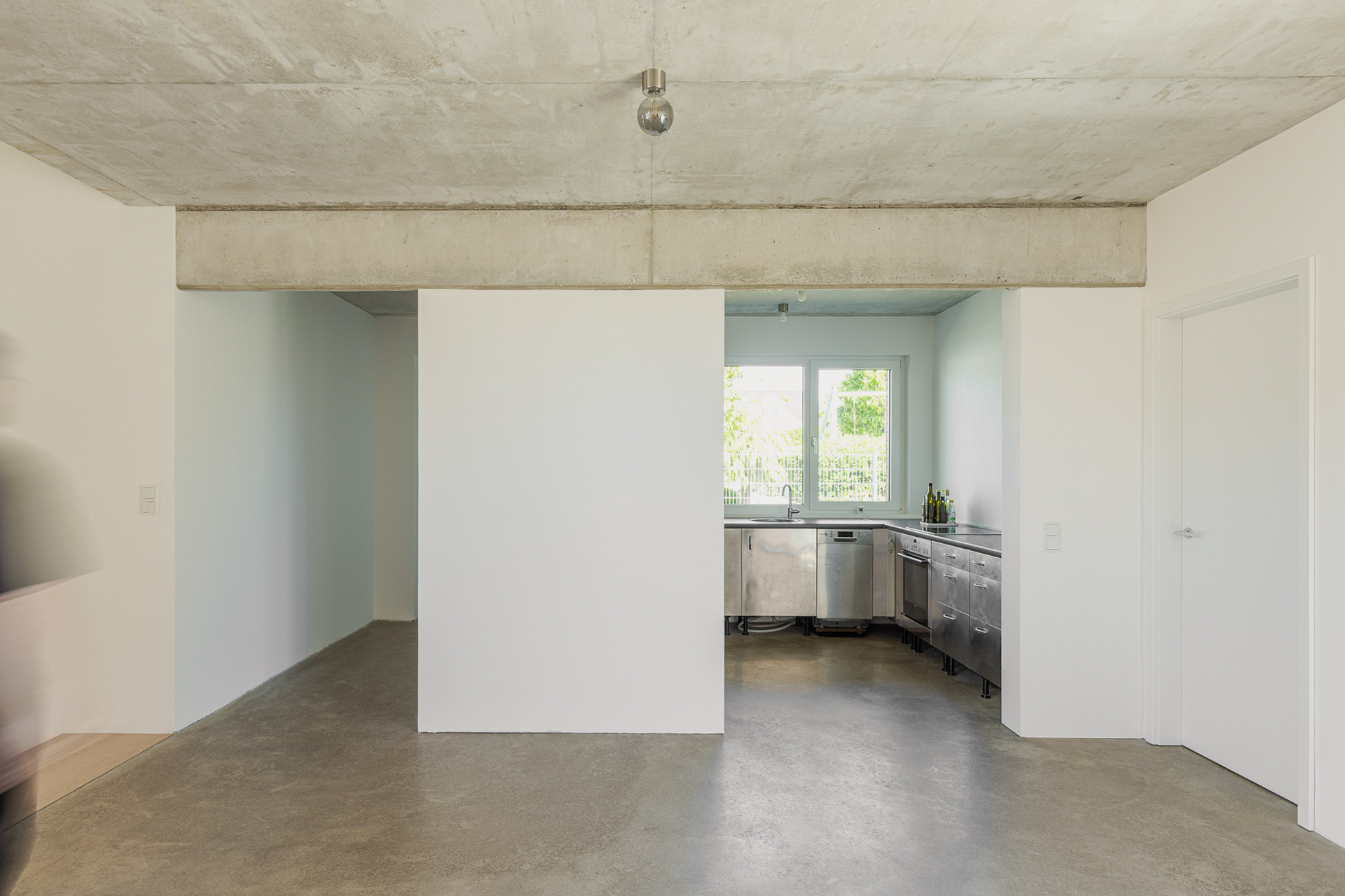Innenraumfoto mit geschliffenem Estrich, weißen Wänden und Sichtbetondecke