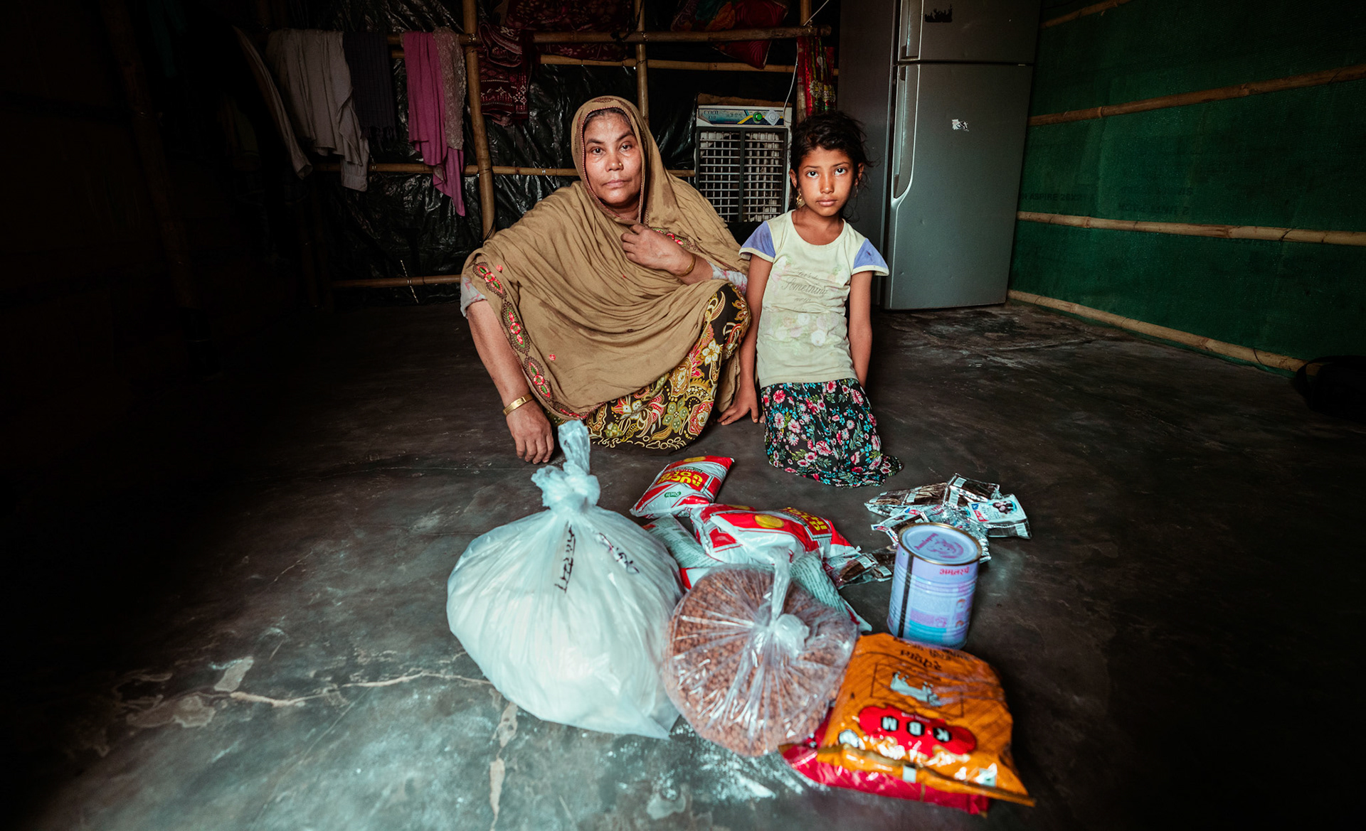 A mother-daughter refugee duo post collecting the essentials distributed during the relief project organised by Catholic Relief Services (CRS) in Mewat, Haryana.