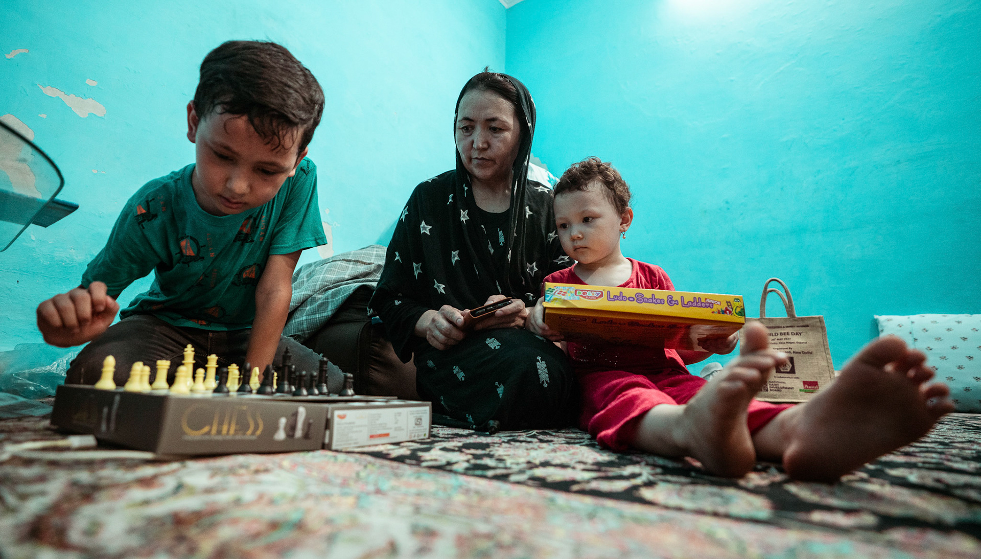 An Afghan refugee mother joins her daughter and her diabetic son as they setup a game of chess at their house in Tilak Nagar, Delhi.