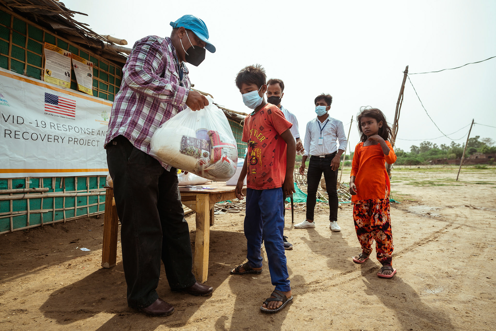 Rohingya Refugee children queuing up to collect the basic need supplies and COVID recovery kits being distributed by Catholic Relief Services (CRS) as a part of Voucher Based Distribution in Mewat, Haryana.