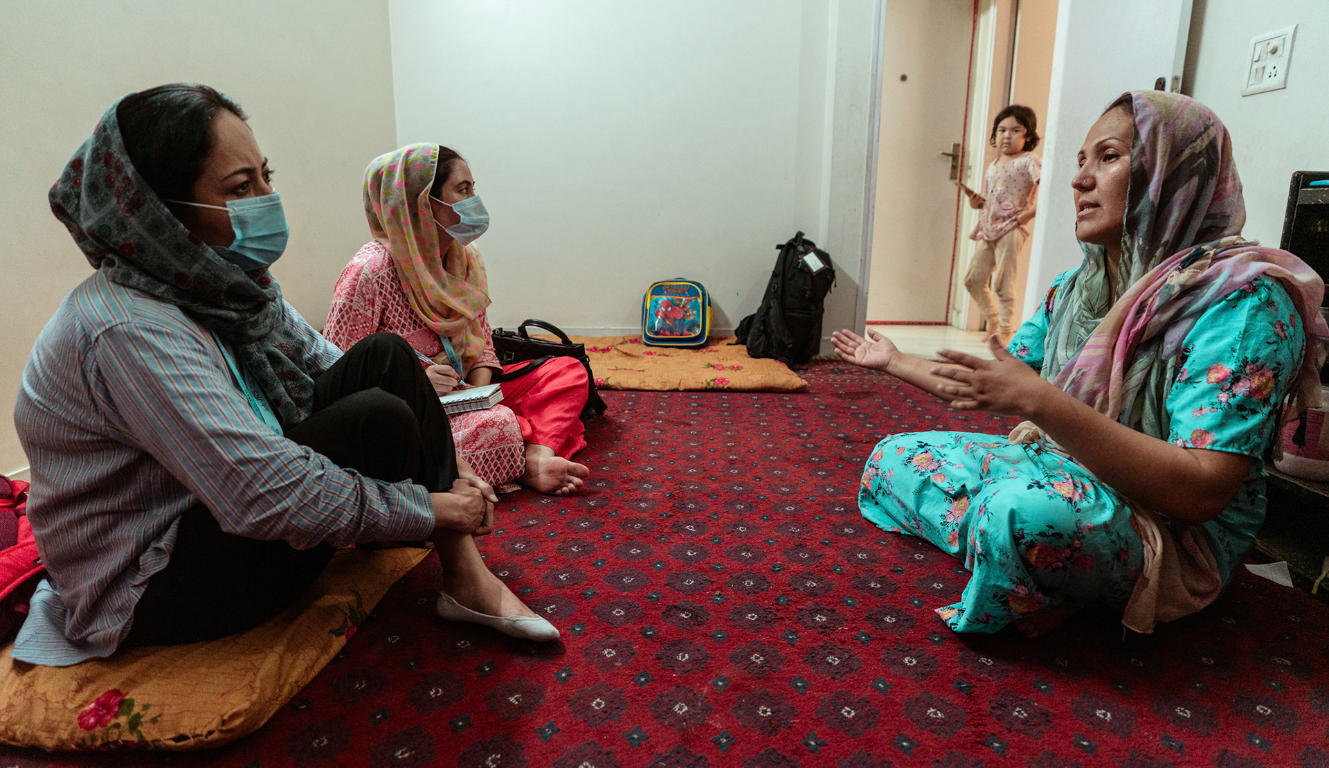 Representatives of Catholic Relief Services (CRS) speaking to a refugee in Tilak Nagar, Delhi about COVID Appropriate Behaviour, Gender based violence and child protection.