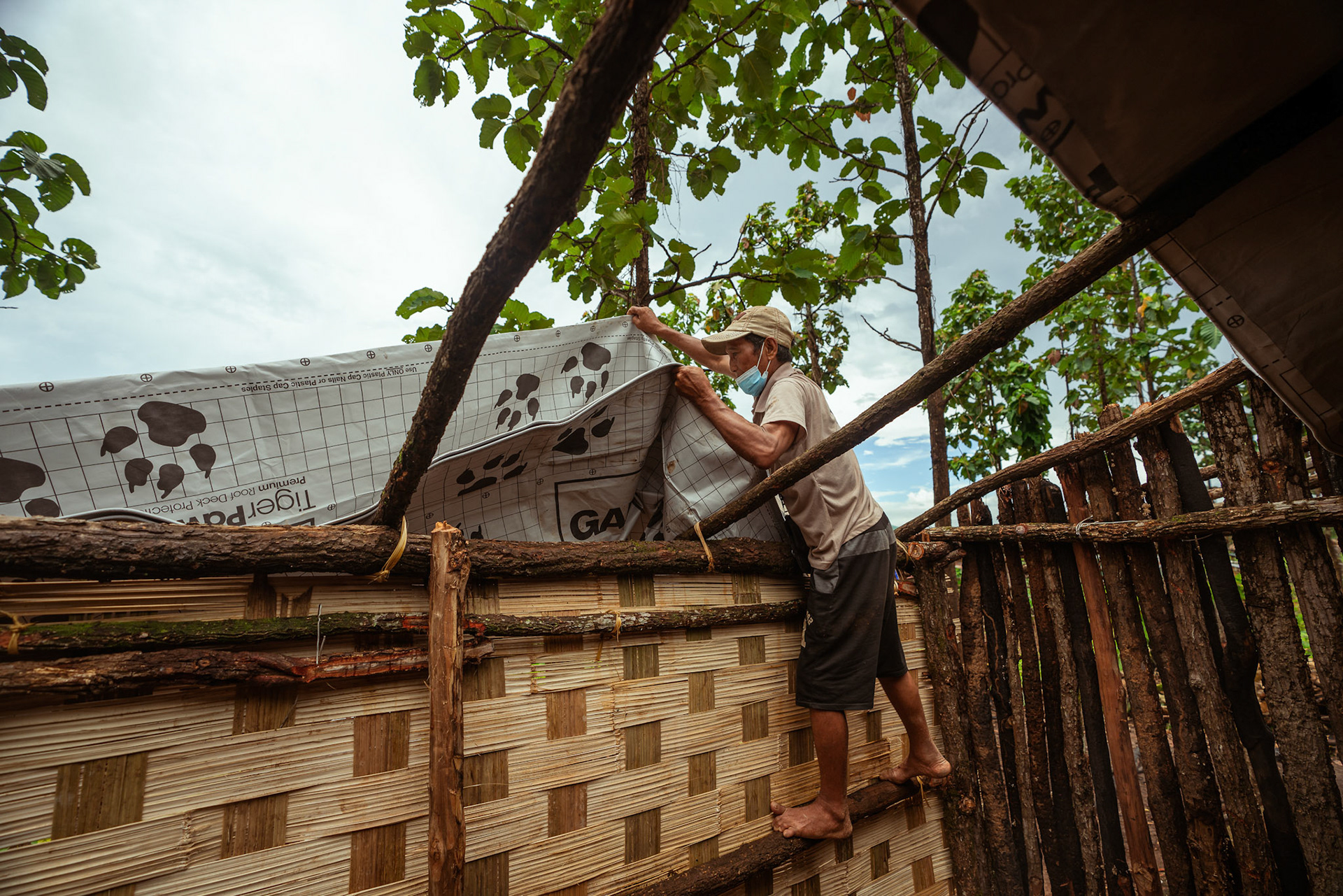 Refugees in Moreh, Manipur, covering their roof with tarpaulin sheets received from the Voucher Based Distribution of basic need supplies and COVID recovery kits among People of Concern (POC) in Moreh, Manipur organised by Catholic Relief Services (CRS).