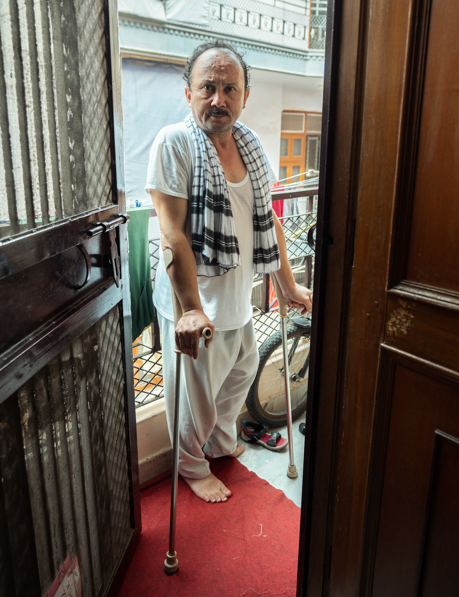 A diffrently abled Afghan refugee, stands at his house entrance in Tilak Nagar, Delhi.