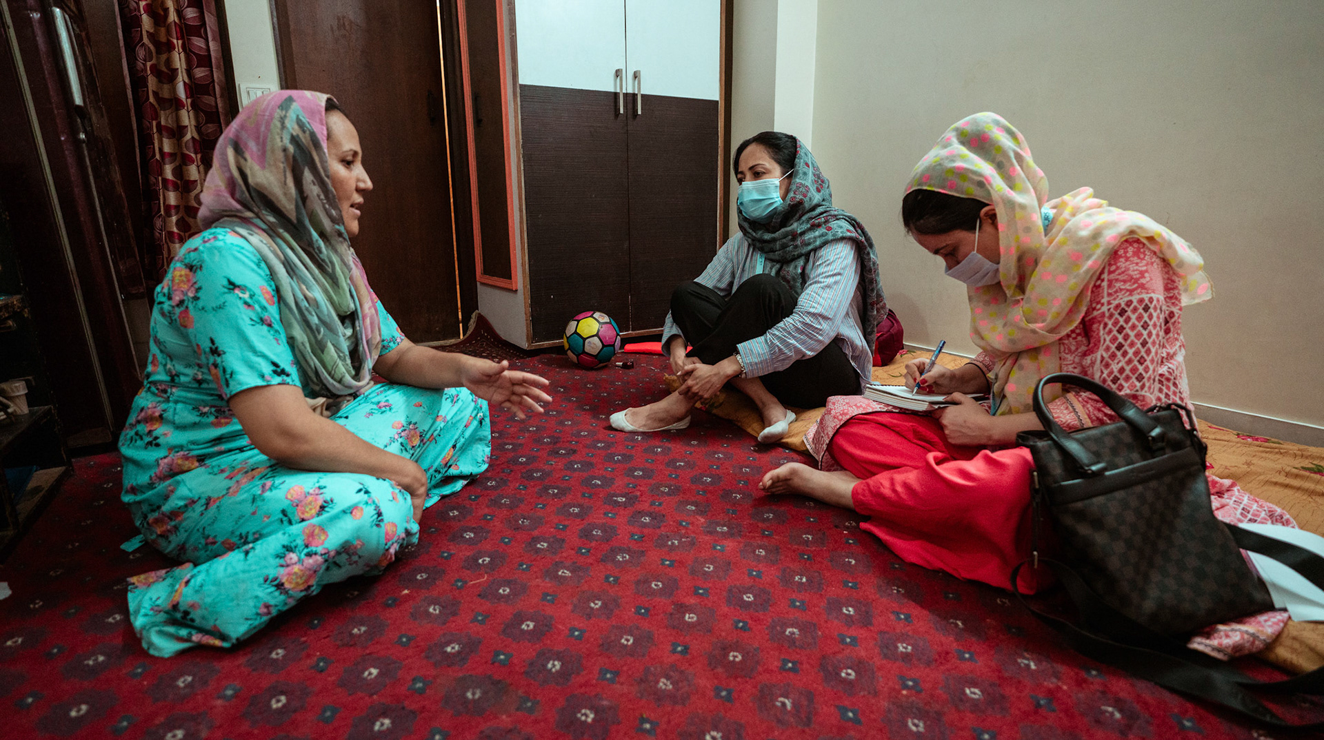 Representatives of Catholic Relief Services (CRS) speaking to a refugee in Tilak Nagar, Delhi about COVID Appropriate Behaviour, Gender based violence and child protection.
