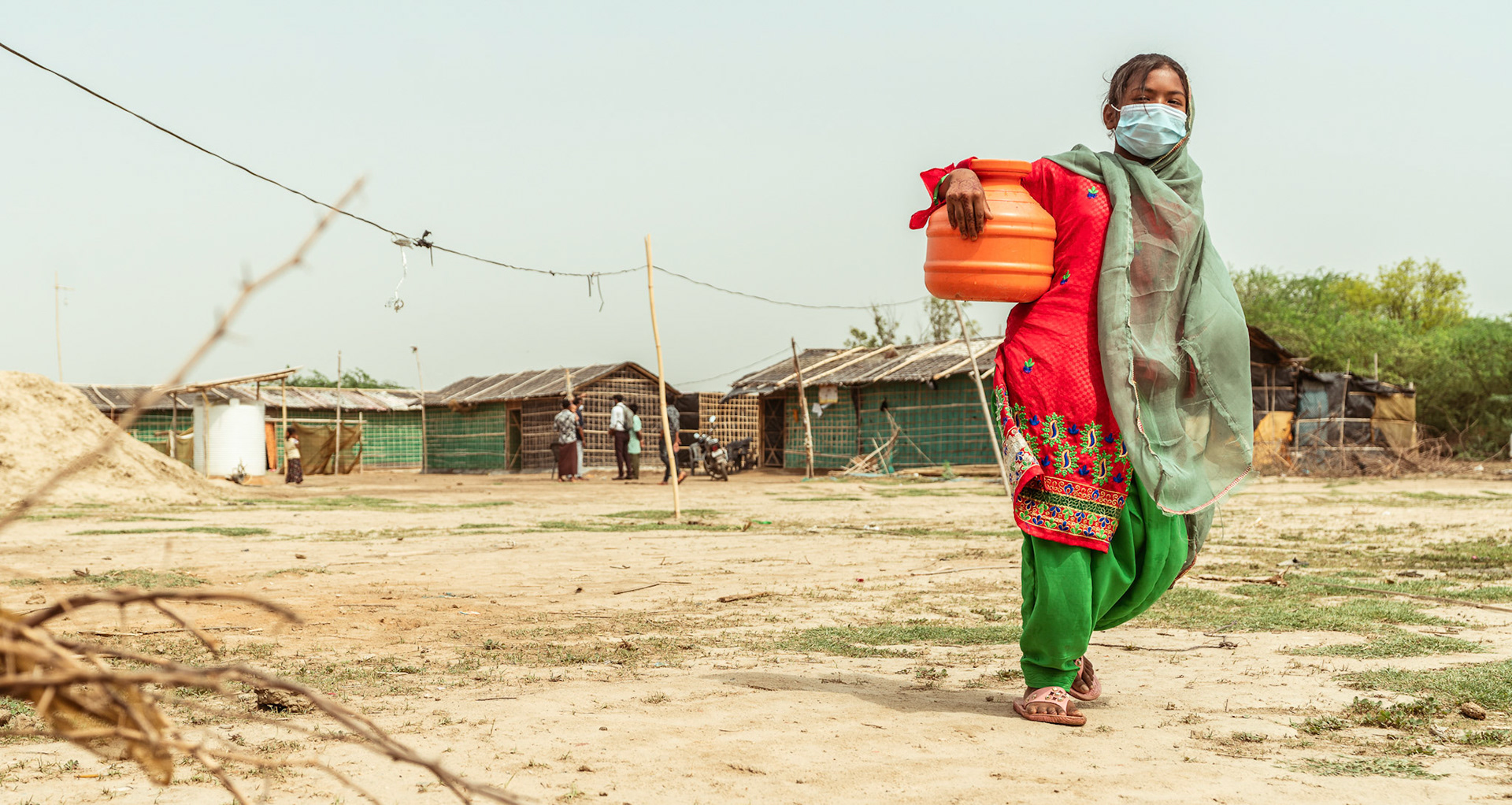 A young Rohingya refugee girl in Mewat, Haryana, carrying a water cannister back home.