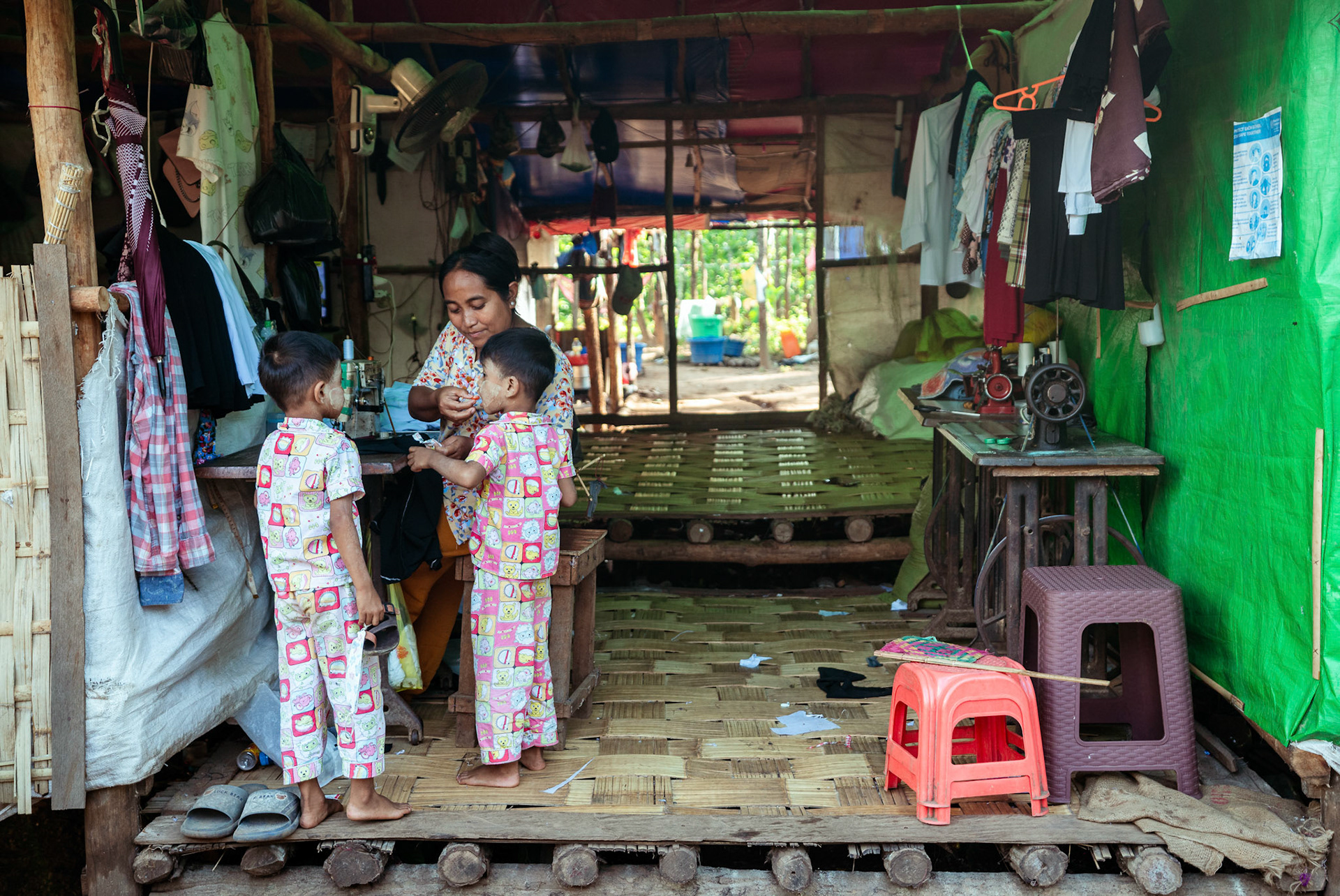 A refugee mother feeding her twins in Moreh, Manipur, and stitching clothes at her home; it comes under the livelihood incubation initiative organised by CRS as a part of COVID-19 Response and Recovery Program.