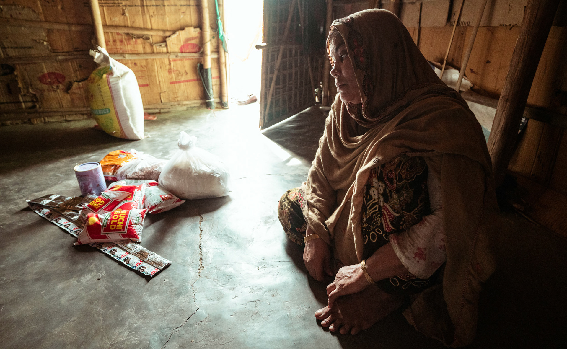 A Rohingya refugee woman sitting with the essentials and COVID recovery kit collected during COVID-19 Response and Recovery Program  organised in Mewat, Haryana.