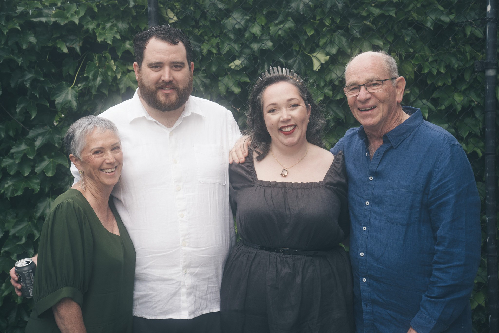 Family photograph at a wedding with the bride and groom and the bride's parents, everyone is very happy
