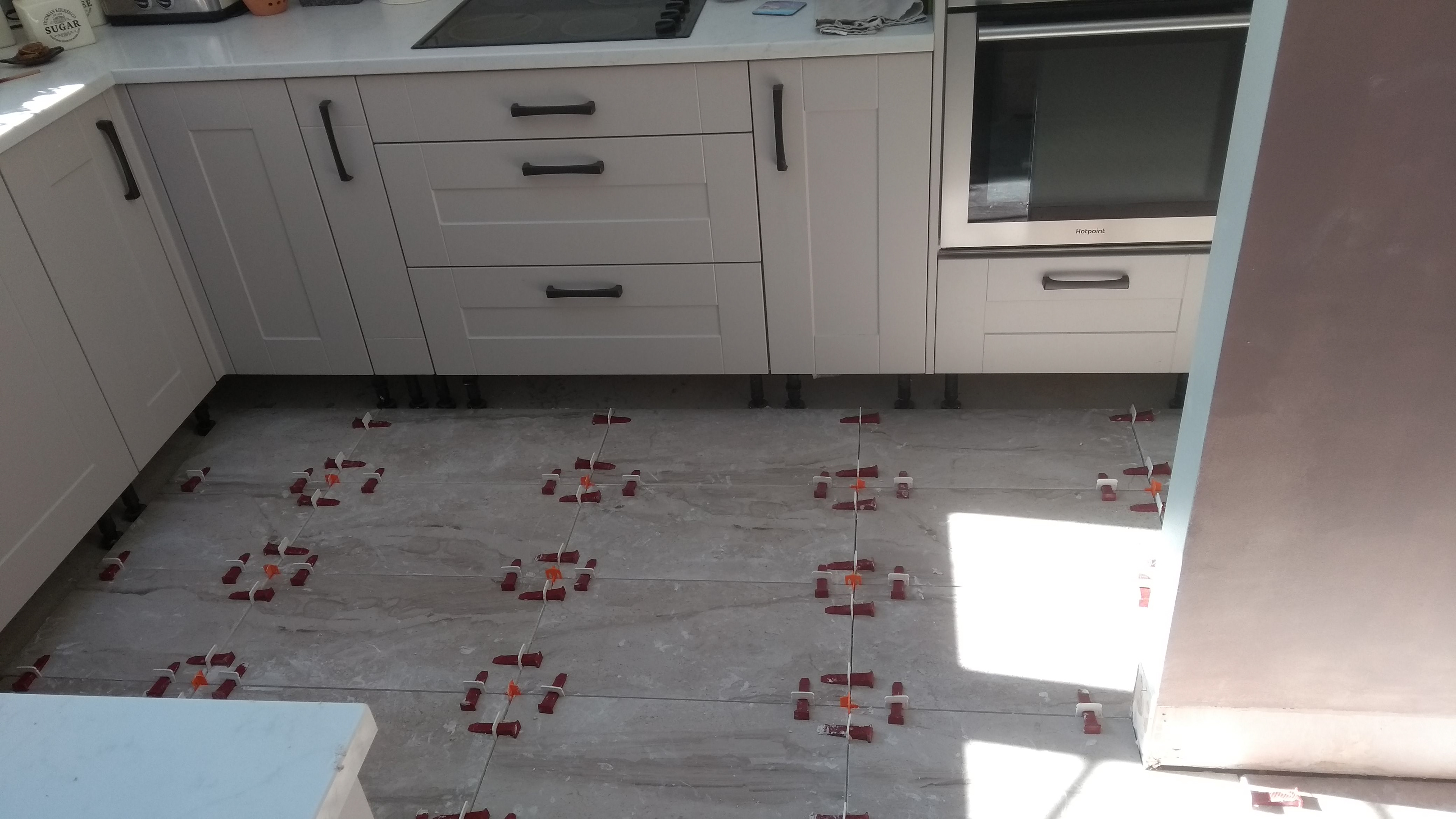New kitchen installation showing floor tiling in progress, prior to fitting of plinths and skirting board