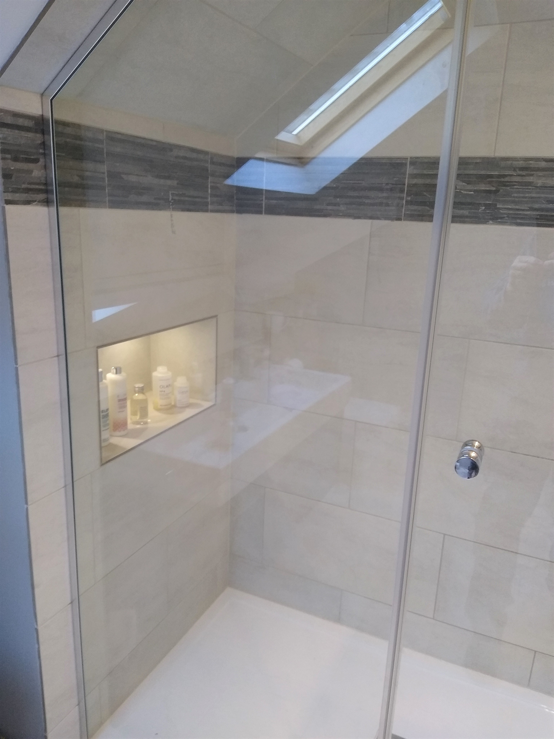 Bespoke glass shower door, templated to follow the ceiling line