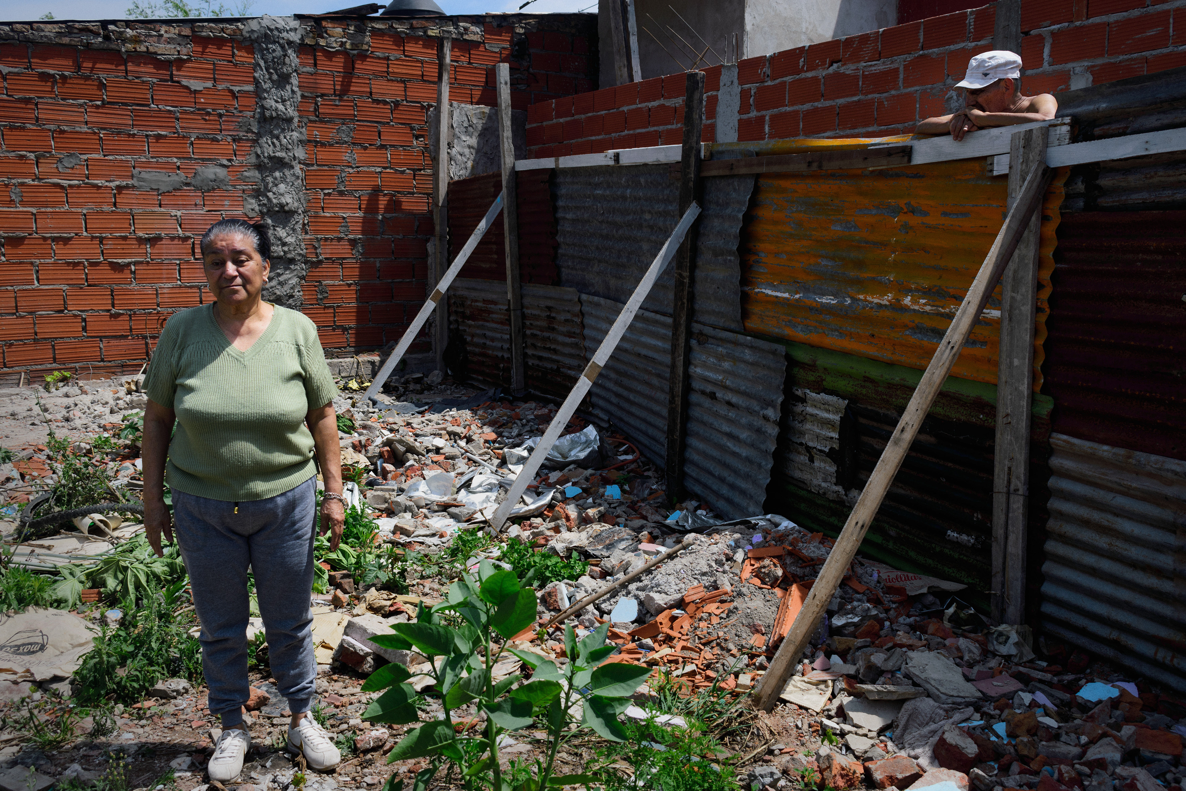 A husband looks over the fence at his wife standing at the entrance to their unfinished home on the riverbank. They are waiting for the Housing Institute of the City of Buenos Aires to relocate them to safer and cleaner housing. Residents living along the riverbank, which snakes around Buenos Aires' southern edge, complain of skin rashes, headaches, breathing problems and vomiting.