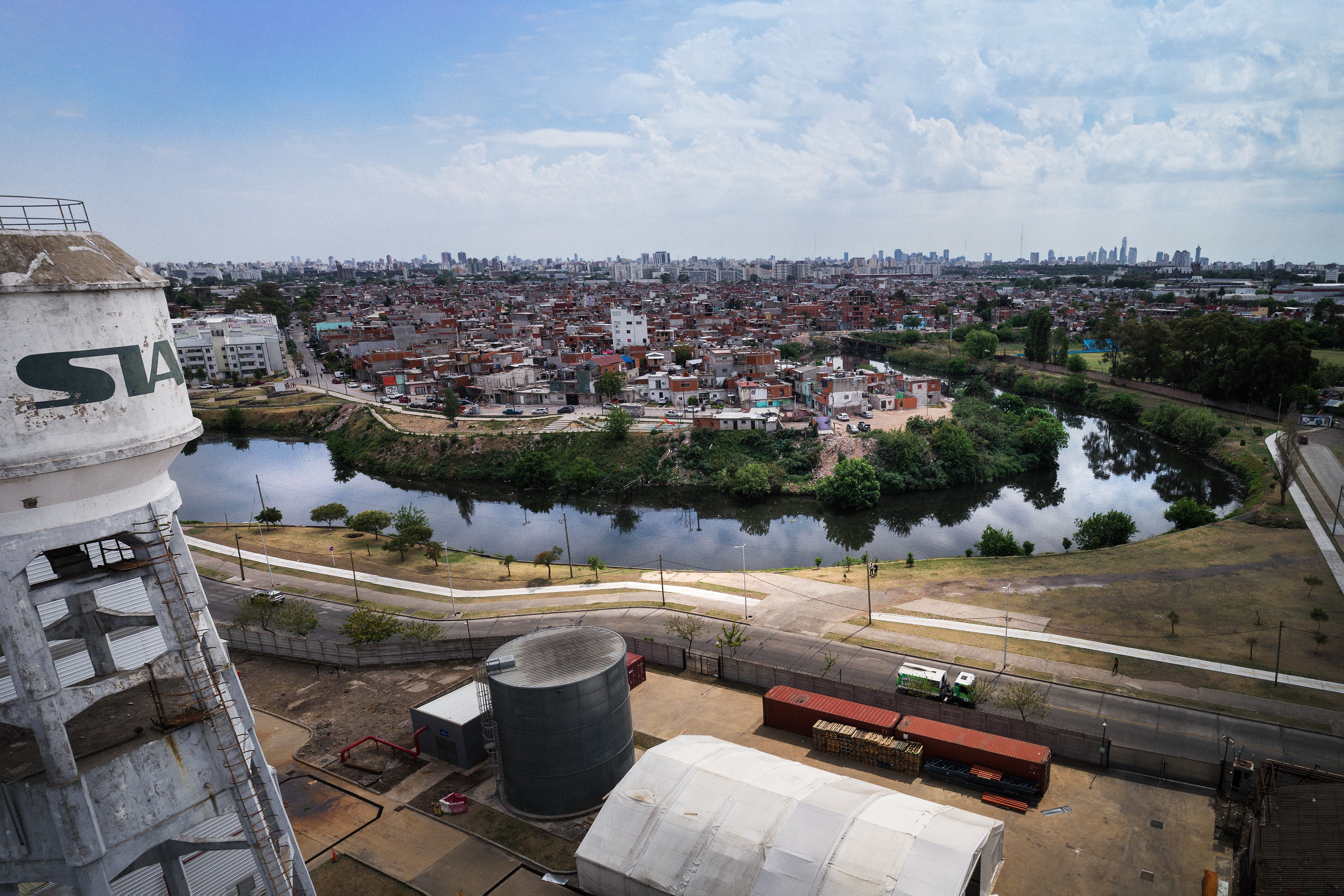 Aerial view of an industrial complex in front of the Riachuelo river. On the other side of the river is the poor Zavaleta neighborhood. Sewers, household waste, old cars and boats, virtually anything fit for a dump went into the river. The result is an environmental and health crisis spanning generations.