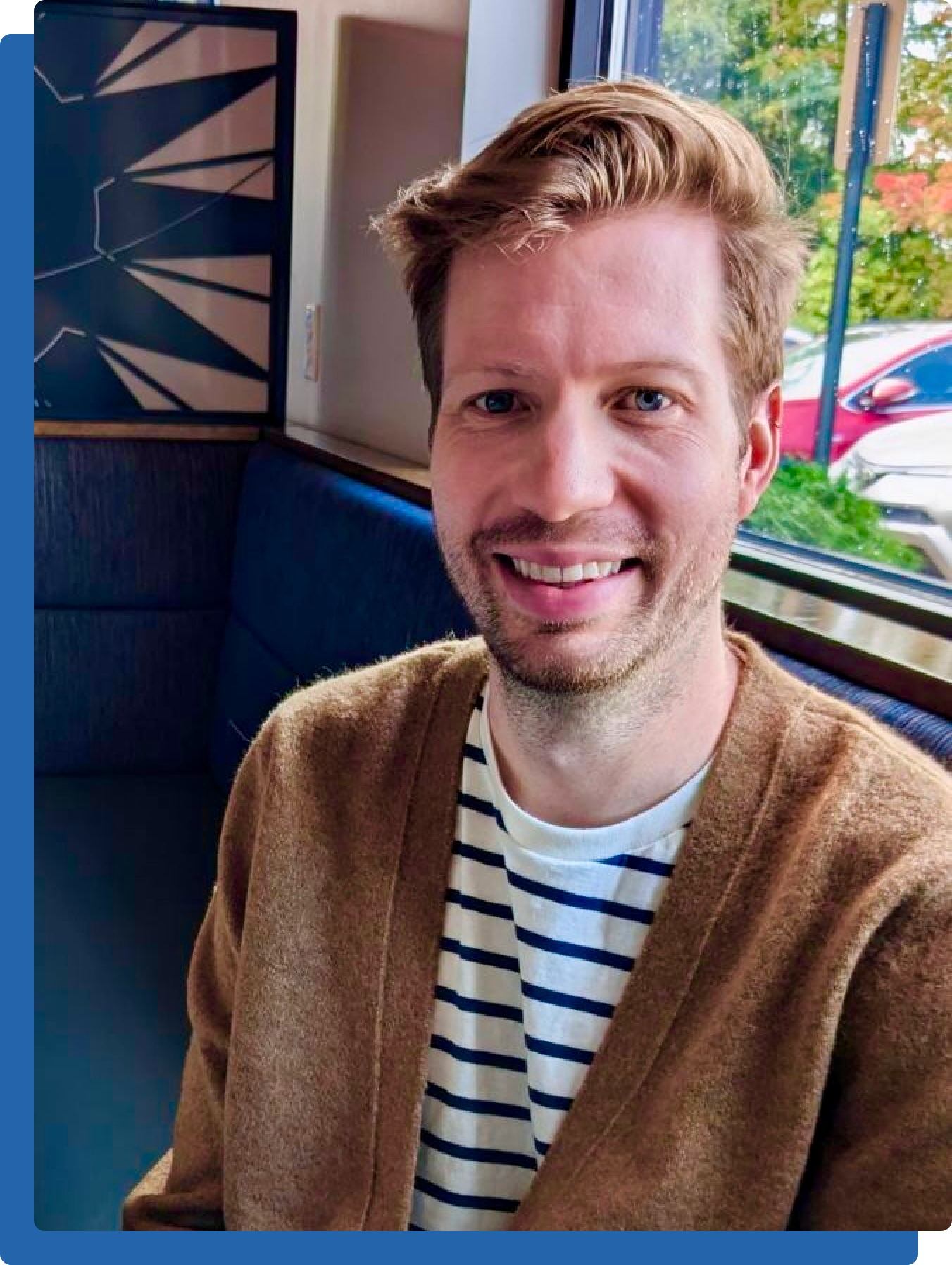 Photo of Charlie smiling while sitting in a booth at a restaurant