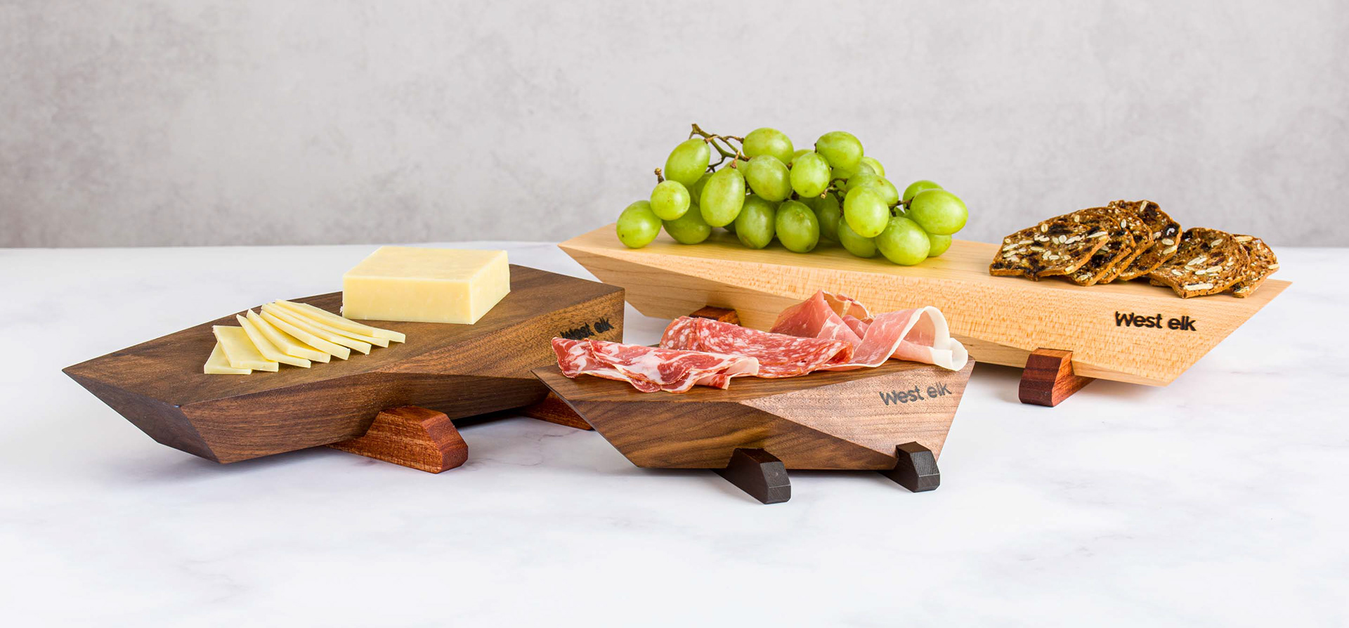 Hardwood custom made serving boards with cheese, grapes, crackers, cold cuts on marble countertop 