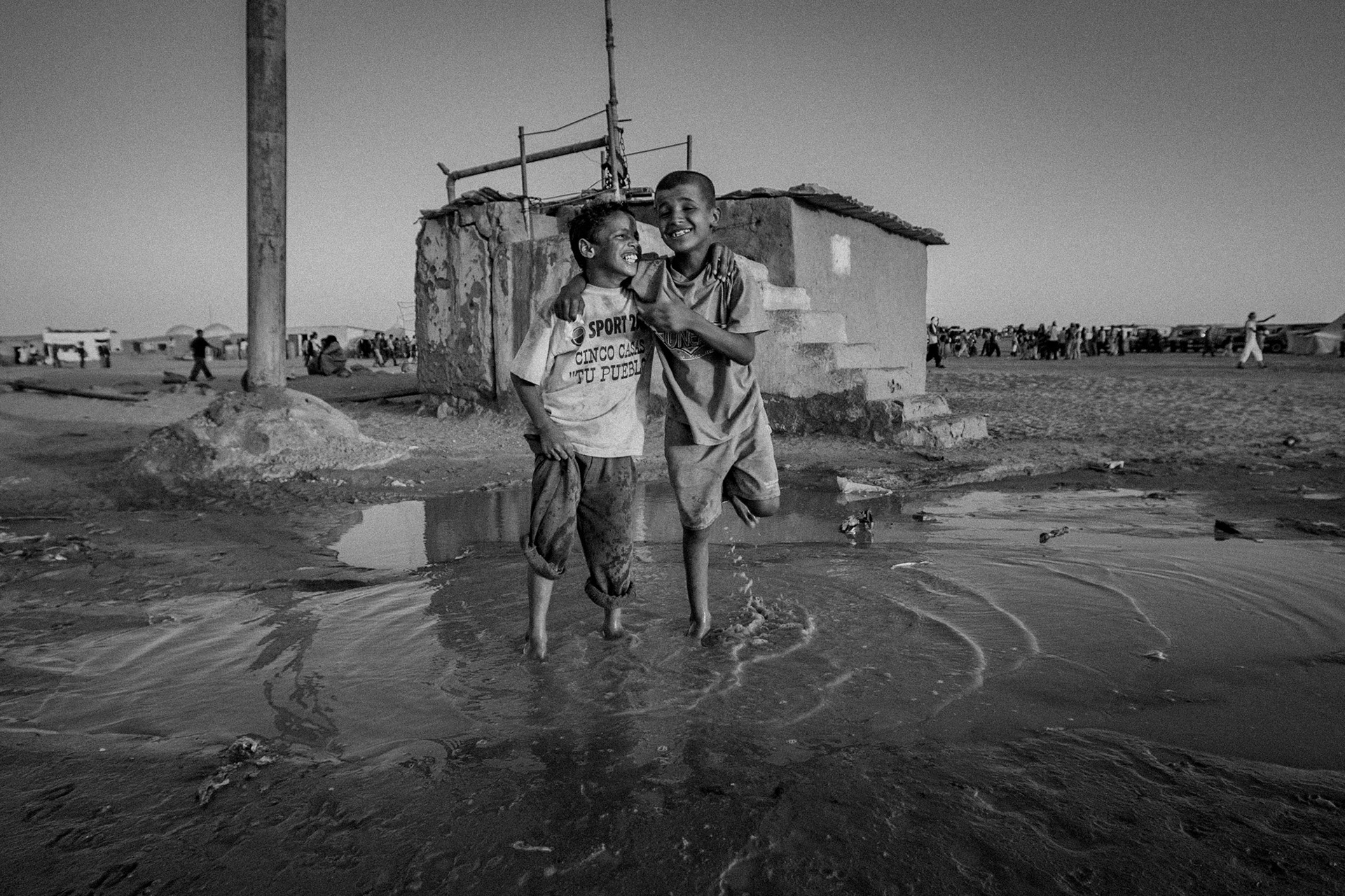 Dakhla refugee camp, Tindouf, Wilaya de Tindouf, Algerian Sahara, 2009: Friends playing with the water of a broken pipe.