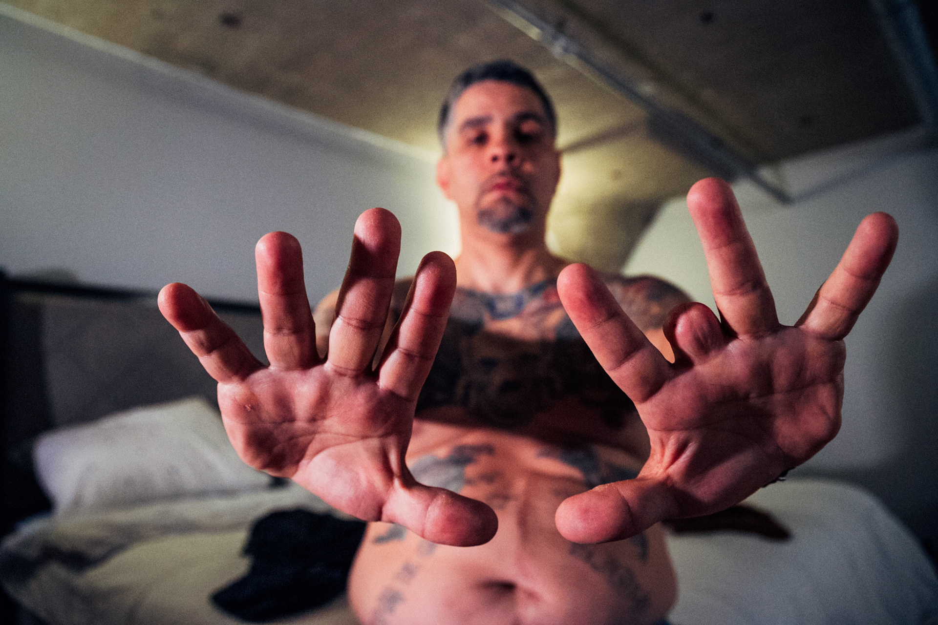Diego Lopez, a former member of the Latin Kings gang in Connecticut, now dedicates his life as a social worker in Hartford, helping others overcome similar struggles. He bears the physical marks of his past – tattoos, scars, and gunshot wounds, including one that resulted in the amputation of a finger. Photographed at his home in Hartford, Connecticut on April 11, 2024, Lopez's story is a powerful testament to resilience and transformation.