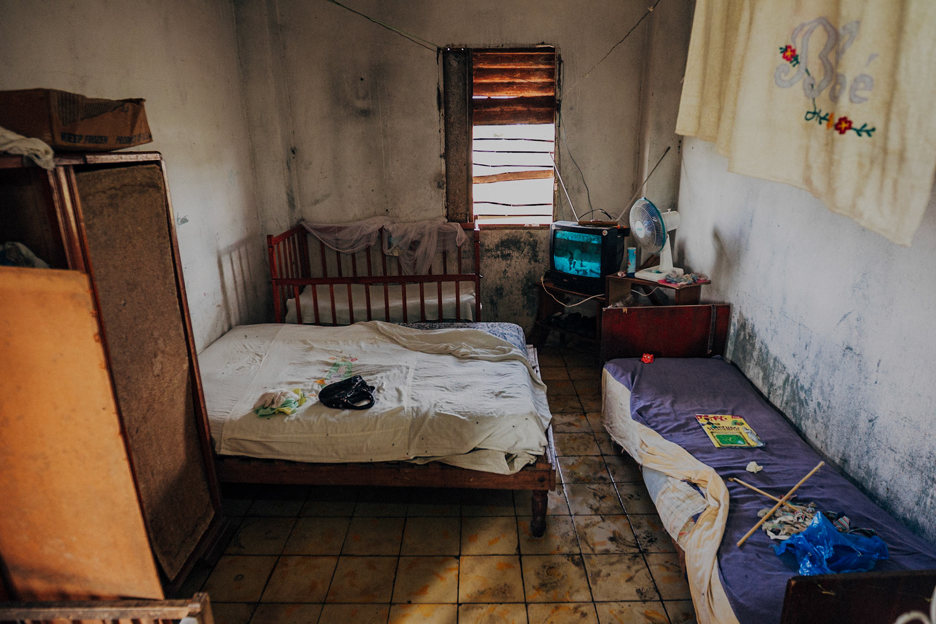 Jatibonico, Cuba — January 1, 2012. On the 54th anniversary of the Cuban Revolution, Yakeline has spent four years waiting for the state housing allocation she was promised. In the meantime, she and her husband raise their five children in the old baseball stadium’s scoreboard building—one room for sleeping, the upper level improvised as a bathroom. With no running water or electricity, they rely on neighbors while hoping for something better.
