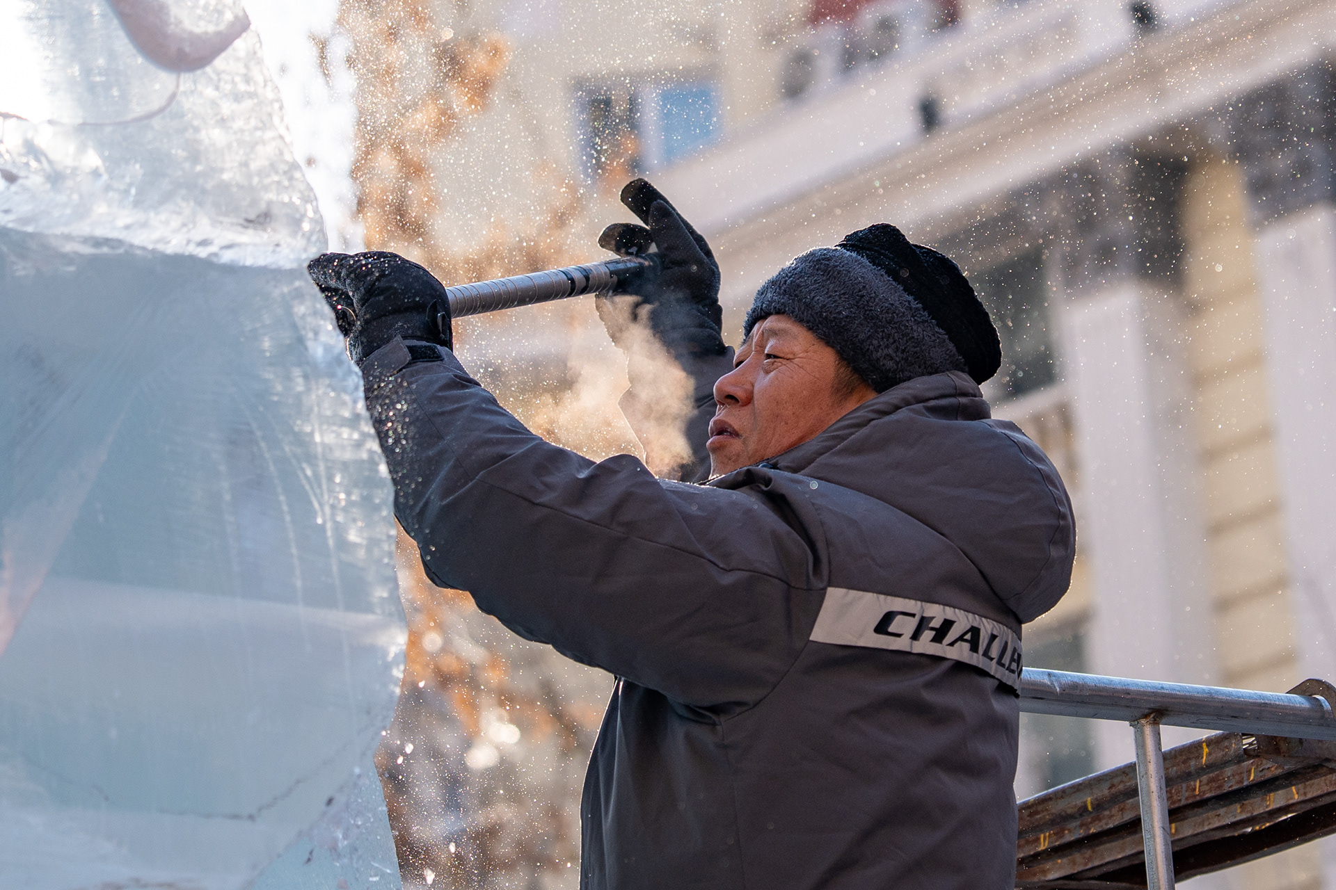 The Ice Carver. A sculptor cuts into the block at first light, breath and ice-spray catching the cold sun. China, Harbin. 2026