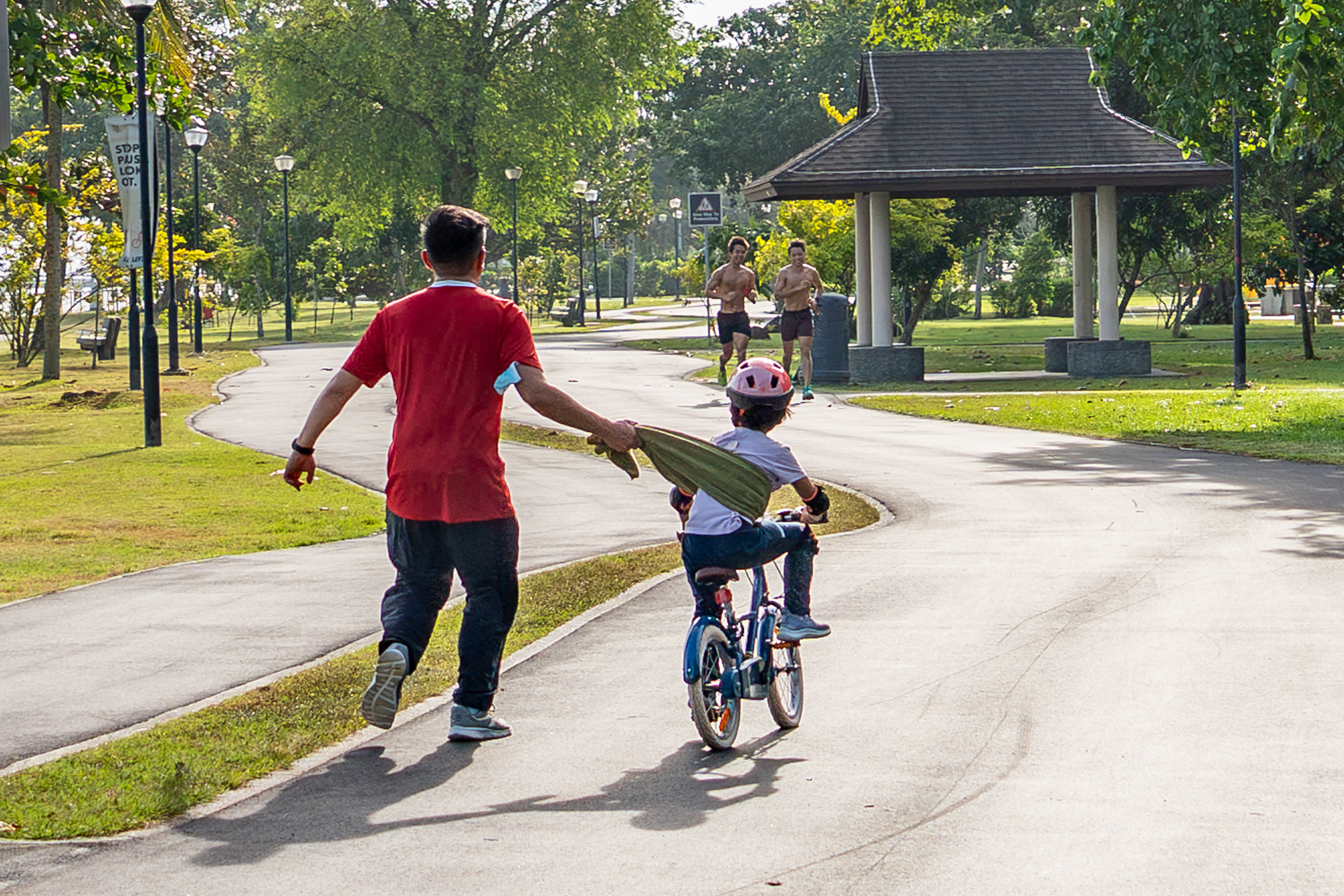 Learning to Ride. A father lets go in the instant his child finds balance. East Coast Park, Singapore 2025.