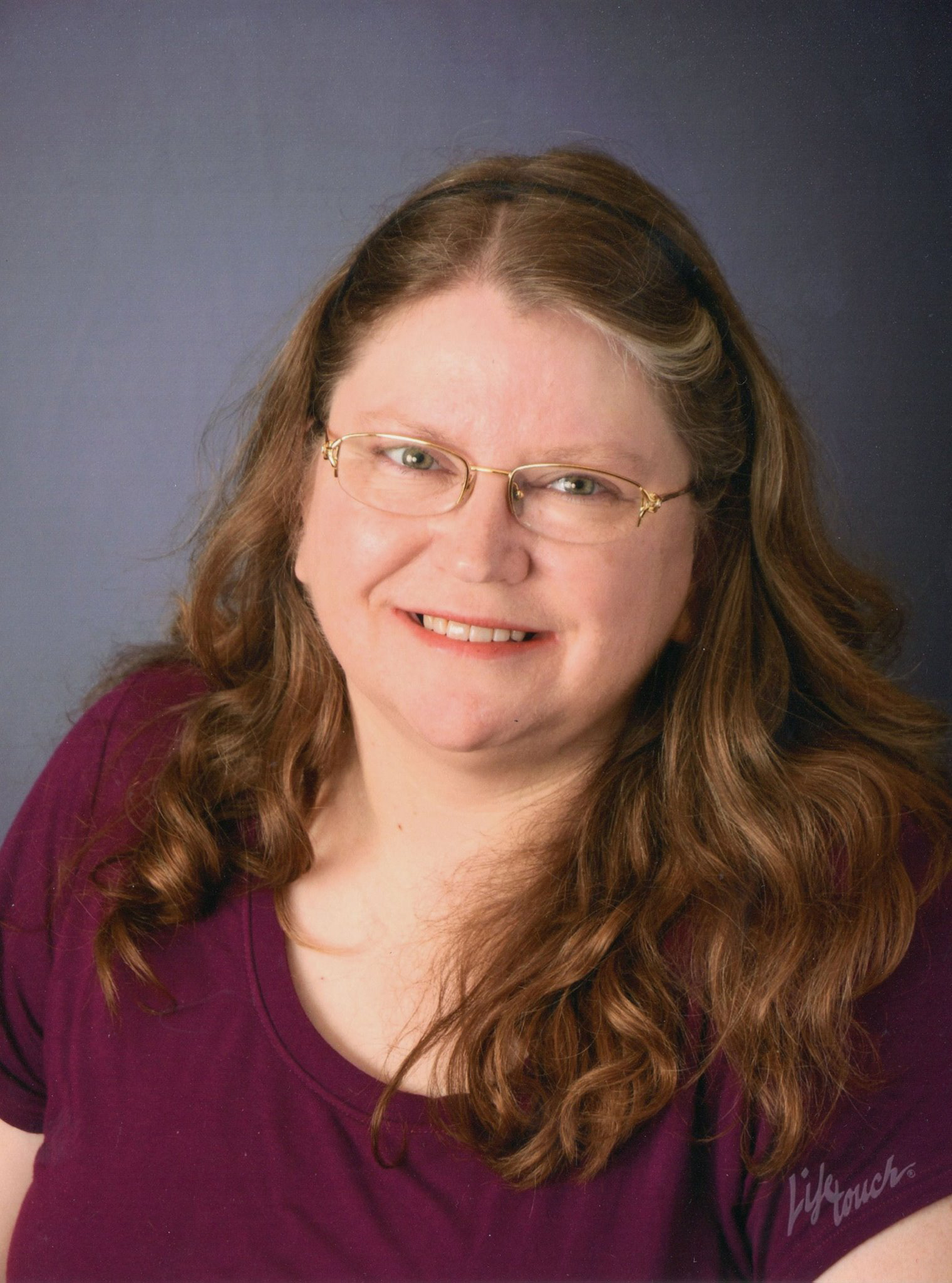 photo of woman with long hair and glasses. She is smiling.