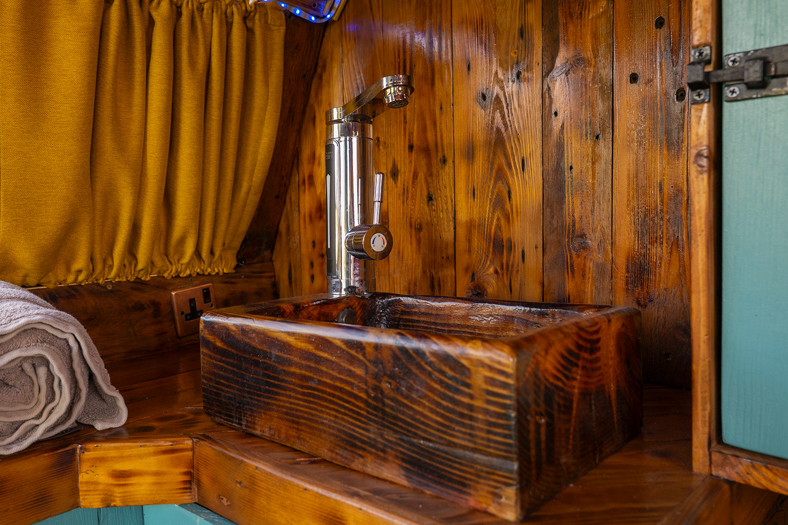 Detail photography of the handcrafted wooden sink in The Pod at Woodlands Farm Wales, highlighting the character and thoughtful practical details of this compact glamping space.